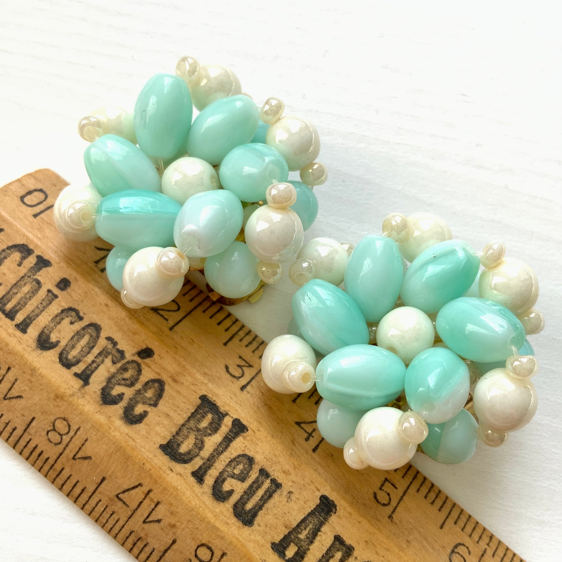 Clip-on earrings featuring floral motifs made from ice blue and white beads. アイスブルーのビーズとホワイトのビーズがお花の形に編まれたクリップイヤリング。