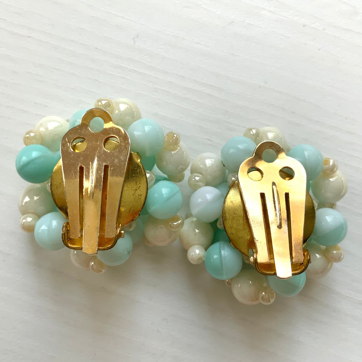 Clip-on earrings featuring floral motifs made from ice blue and white beads. アイスブルーのビーズとホワイトのビーズがお花の形に編まれたクリップイヤリング。