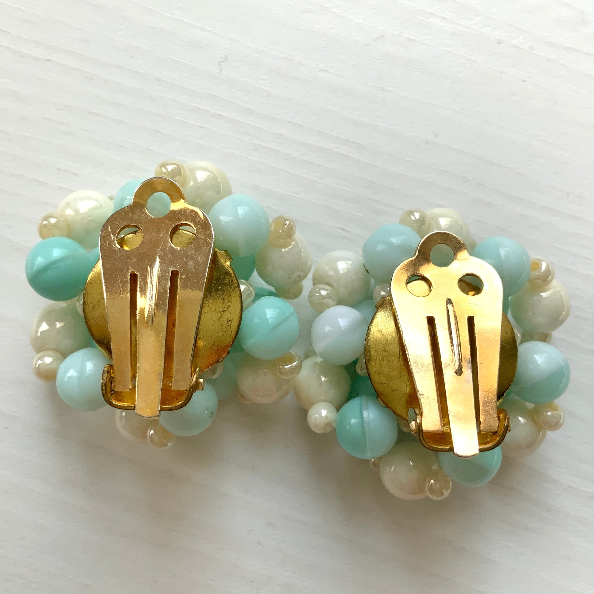 Clip-on earrings featuring floral motifs made from ice blue and white beads. アイスブルーのビーズとホワイトのビーズがお花の形に編まれたクリップイヤリング。