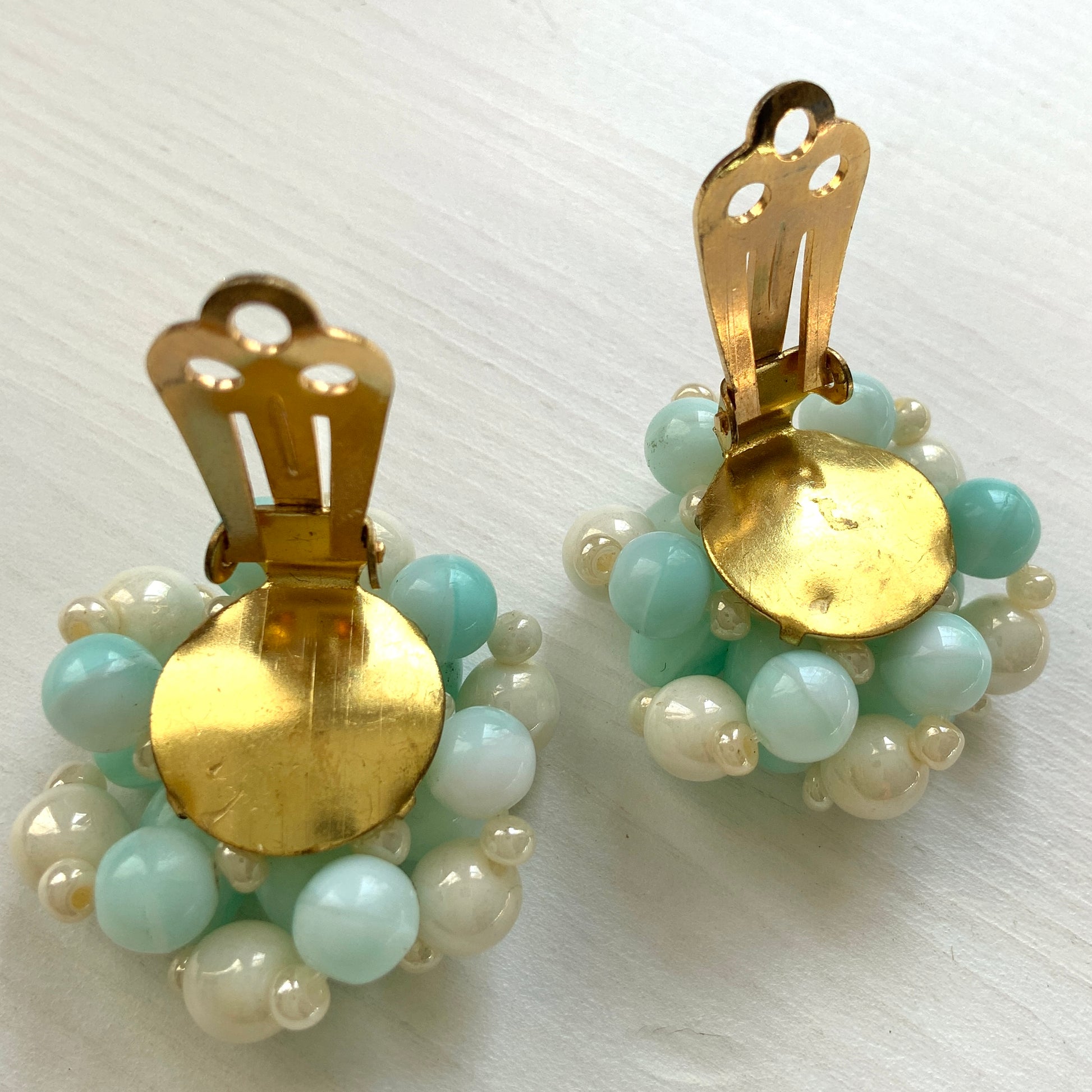 Clip-on earrings featuring floral motifs made from ice blue and white beads. アイスブルーのビーズとホワイトのビーズがお花の形に編まれたクリップイヤリング。