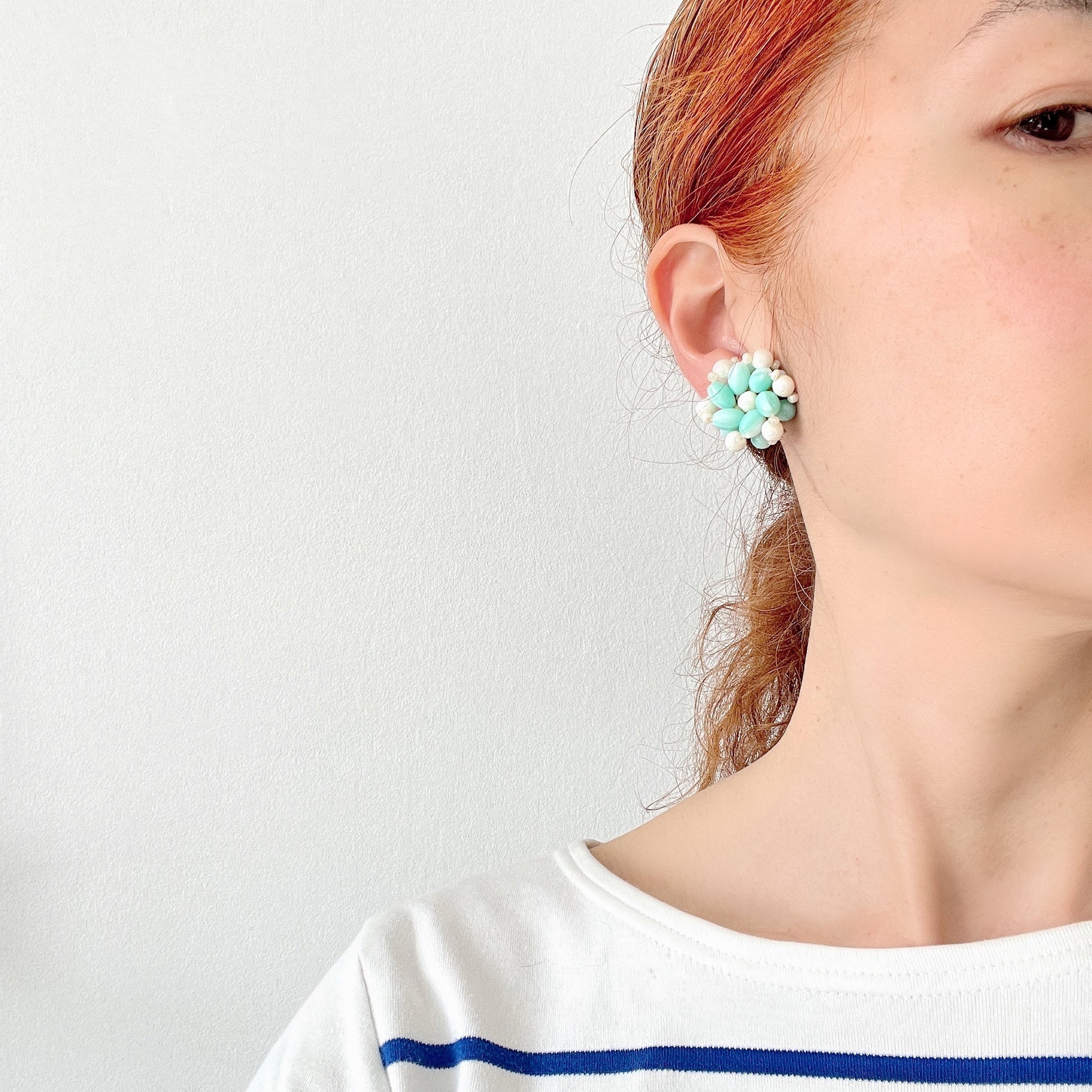 Clip-on earrings featuring floral motifs made from ice blue and white beads. アイスブルーのビーズとホワイトのビーズがお花の形に編まれたクリップイヤリング。