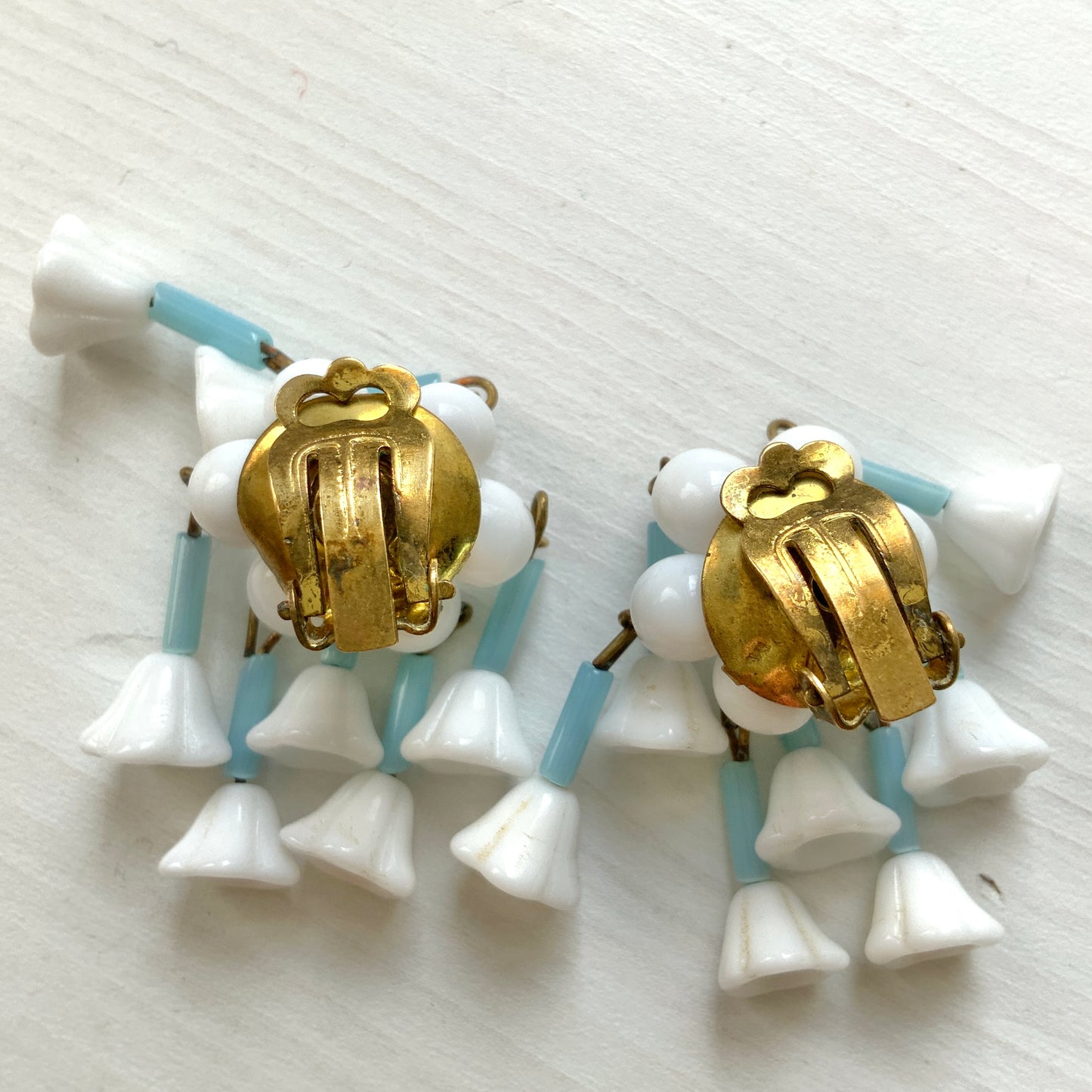 These clip-on earrings feature a waterfall design with white glass flower beads that gently dangle. 白いお花のグラスビーズがゆれるウォーターフォールスタイルのクリップイヤリング。