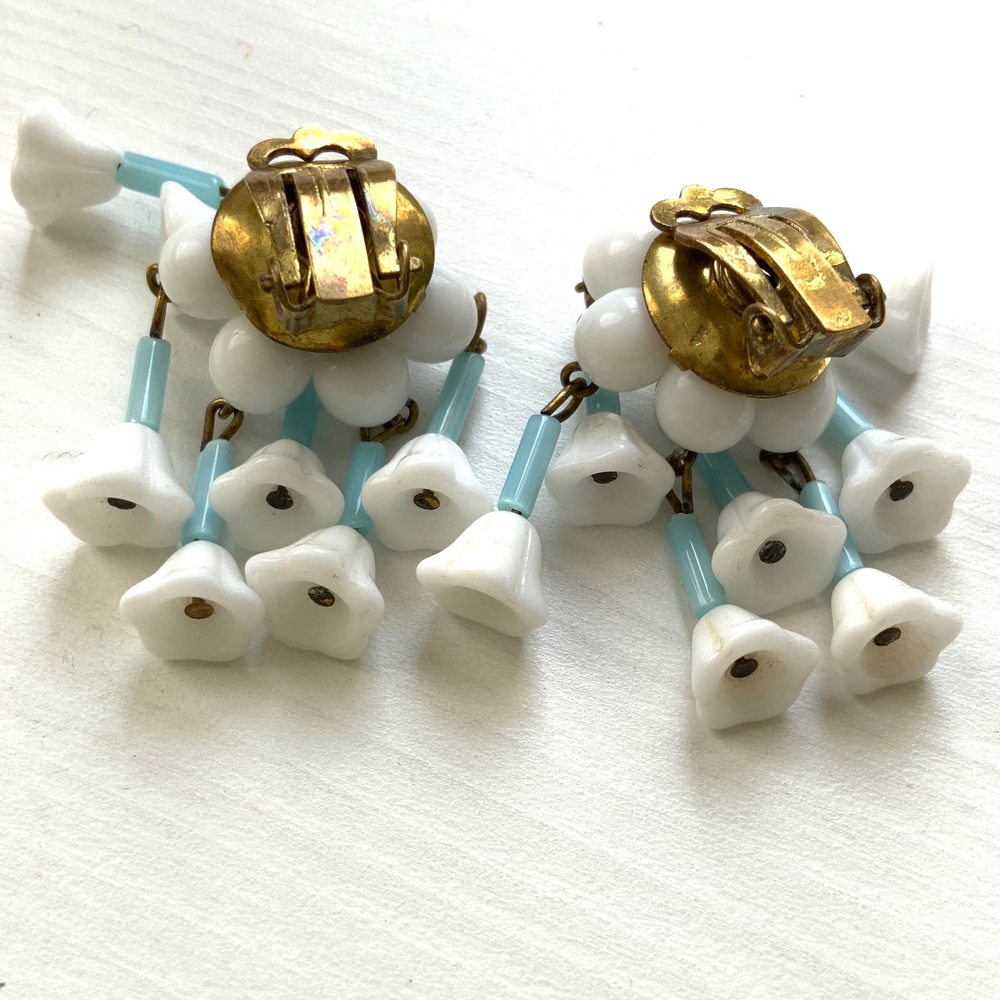 These clip-on earrings feature a waterfall design with white glass flower beads that gently dangle. 白いお花のグラスビーズがゆれるウォーターフォールスタイルのクリップイヤリング。