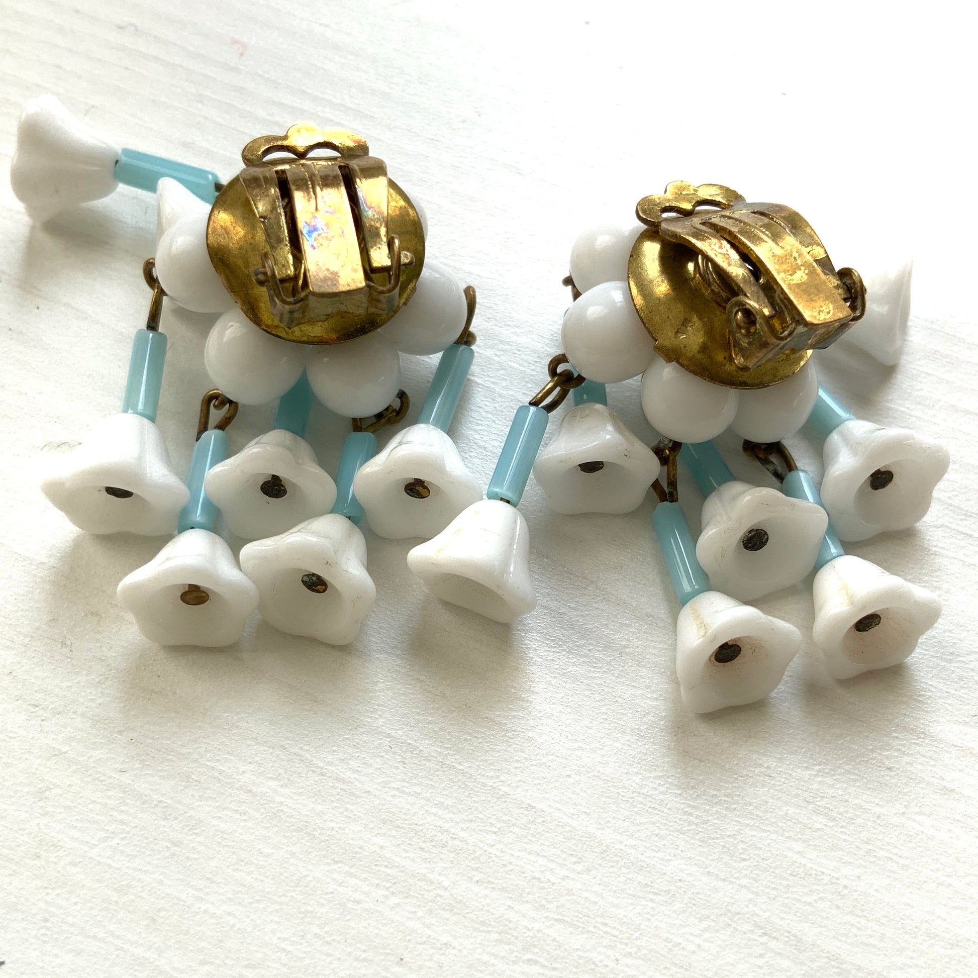 These clip-on earrings feature a waterfall design with white glass flower beads that gently dangle. 白いお花のグラスビーズがゆれるウォーターフォールスタイルのクリップイヤリング。