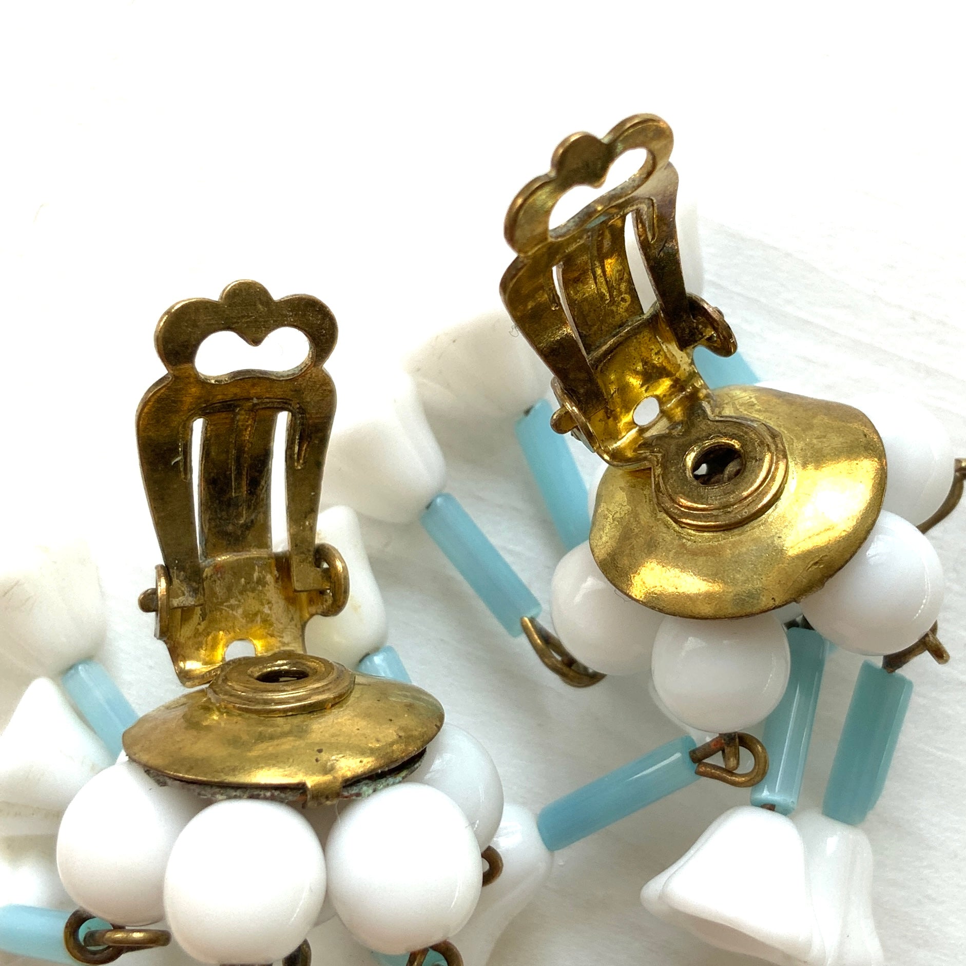 These clip-on earrings feature a waterfall design with white glass flower beads that gently dangle. 白いお花のグラスビーズがゆれるウォーターフォールスタイルのクリップイヤリング。
