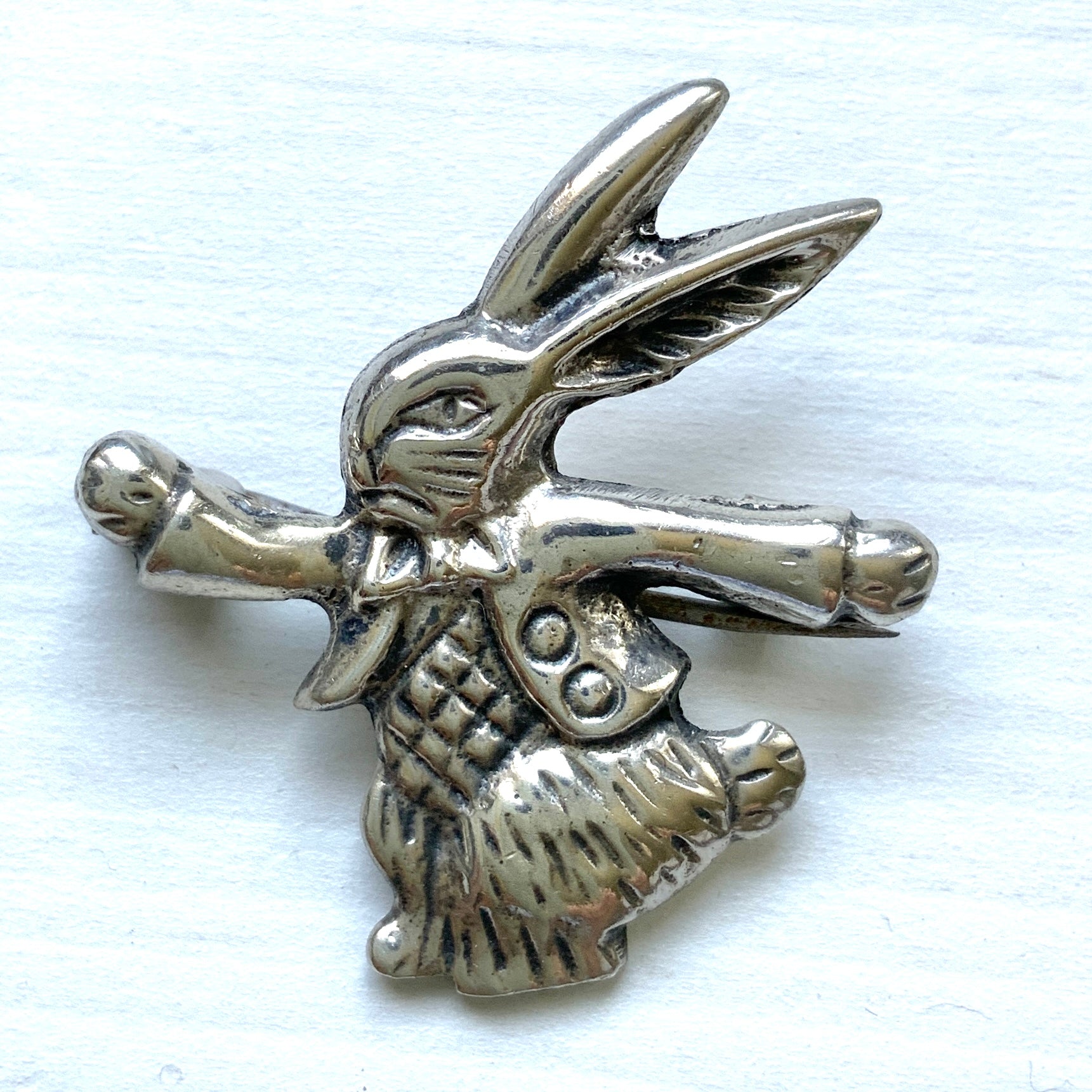 This silver brooch features a rabbit dressed in a waistcoat and jacket. ベストとジャケットを着たうさぎのシルバーブローチ。