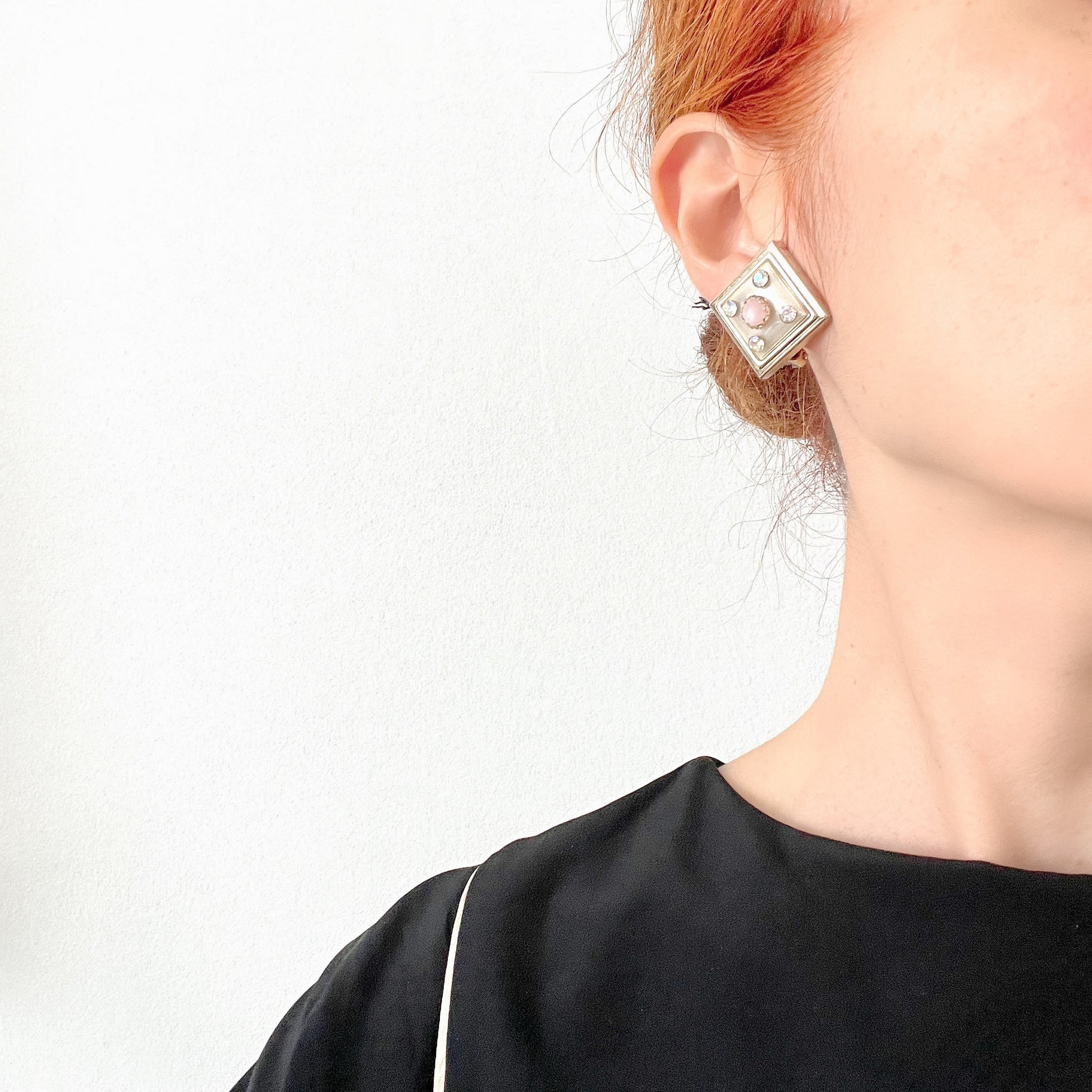 Clip-on earrings featuring white square plastic made to resemble mother of pearl, accented with pink plastic cabochons and shimmering aurora borealis stones. マザーオブパールを模したホワイトのスクエアプラスチックに、ピンクのプラスチックカボションとオーロラストーンが輝くクリップイヤリング。