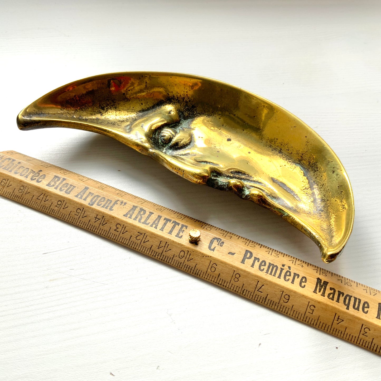 A vintage brass crescent moon ashtray featuring a serene expression. 穏やかな表情を浮かべた三日月が印象的なヴィンテージの真鍮製アッシュトレイ。