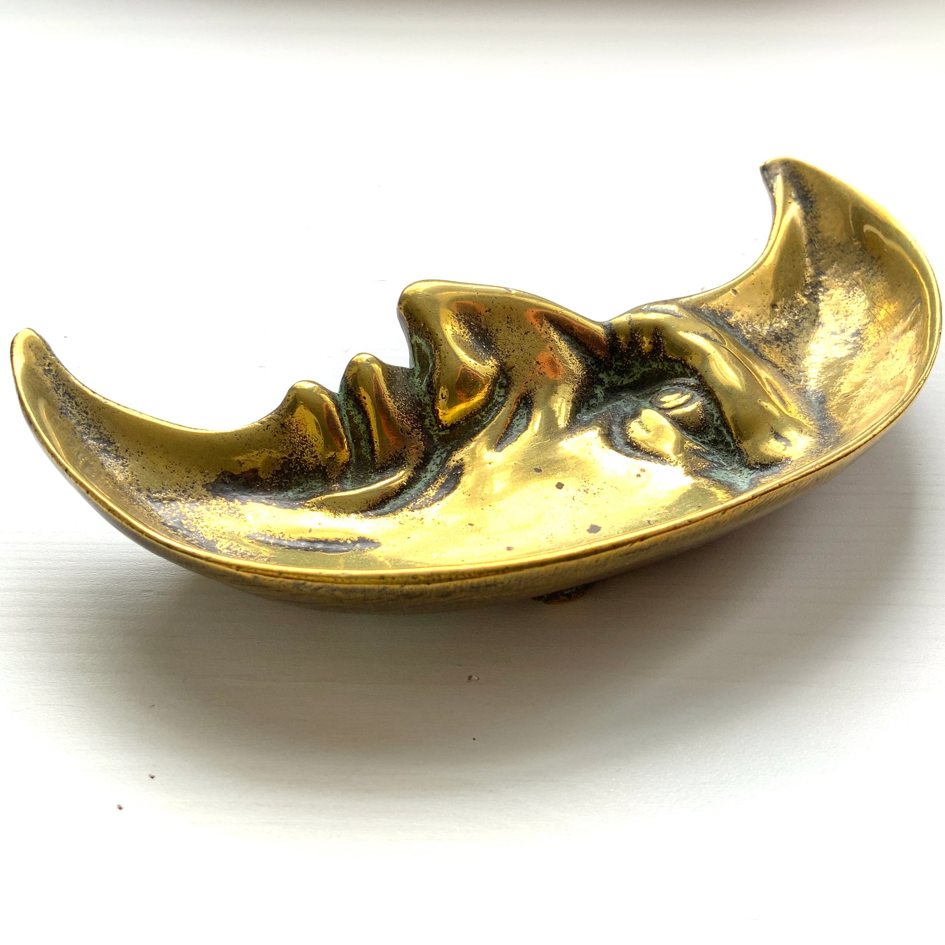A vintage brass crescent moon ashtray featuring a serene expression. 穏やかな表情を浮かべた三日月が印象的なヴィンテージの真鍮製アッシュトレイ。