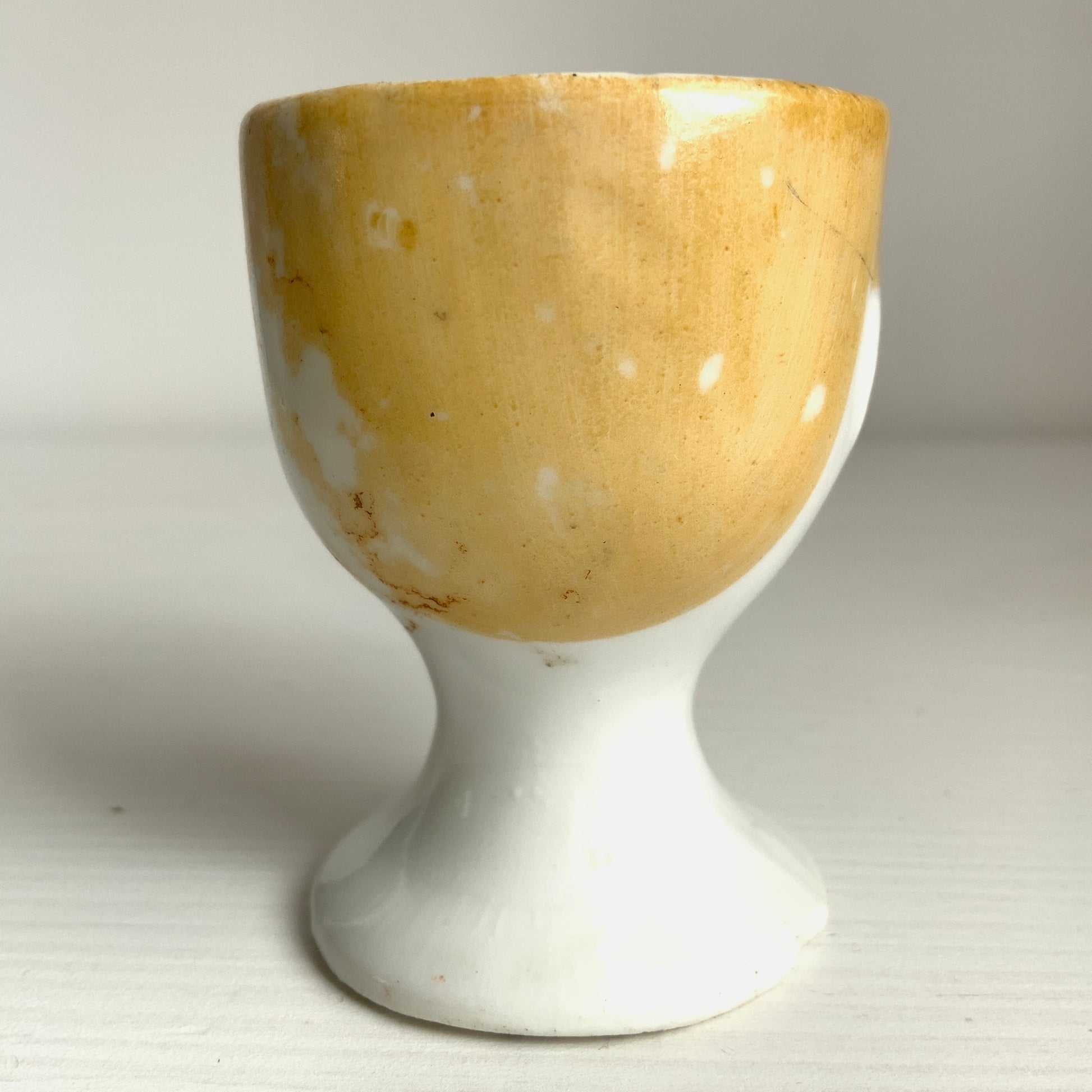 A charming vintage egg cup featuring a smiling child with blue eyes and blonde hair. ブルーアイズとブロンドヘアが印象的な、愛らしい笑顔を浮かべた子どもの顔のヴィンテージエッグカップ。 