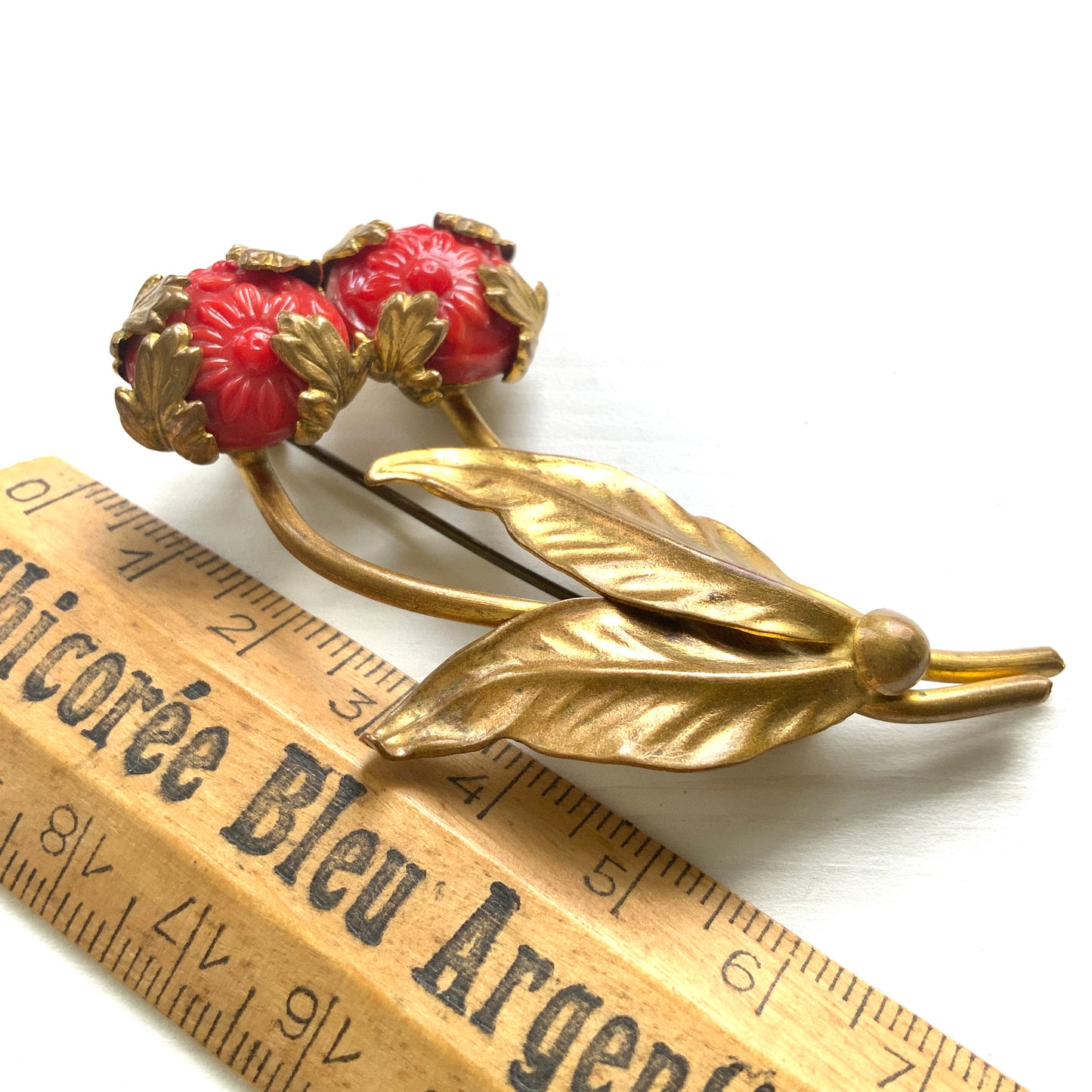 A vibrant 1940s vintage brooch featuring a pressed red glass flower. 鮮やかな赤い型押しガラスのお花が印象的な、1940年代のヴィンテージブローチ。