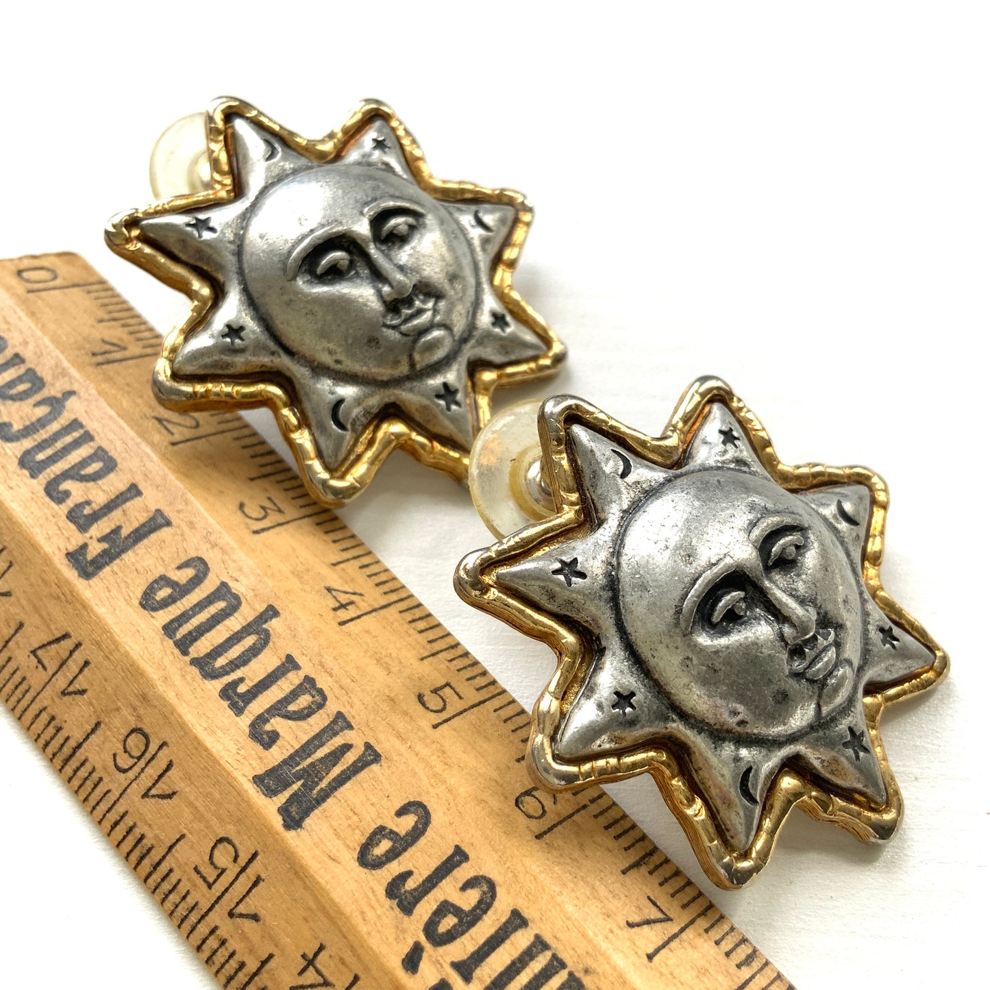 A charming pair of JJ sun earrings featuring a gentle smiling face.  穏やかな微笑みをたたえた、JJの太陽ピアス。 
