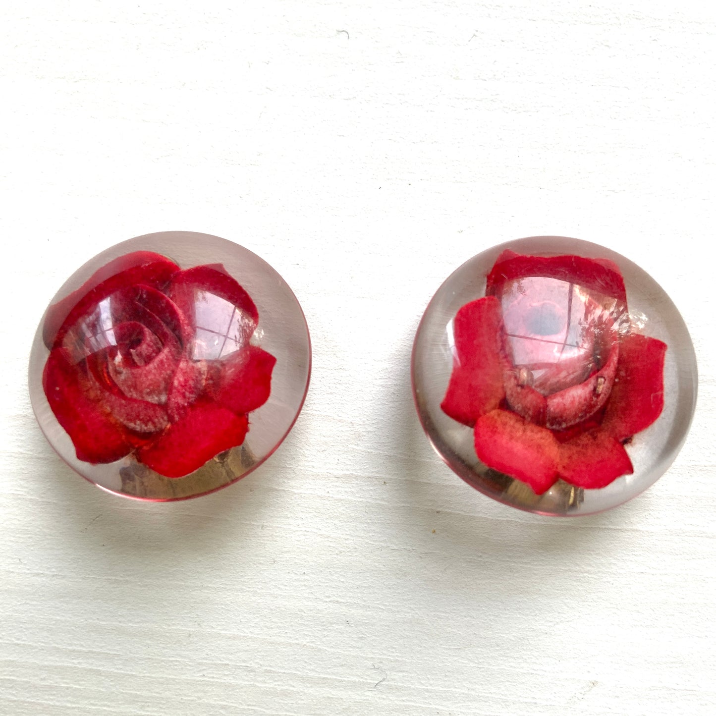 A beautiful pair of 1950s clip-on earrings featuring vivid red roses reverse carved into clear Lucite.  1950年代の赤いバラのインタリオのヴィンテージクリップイヤリング。