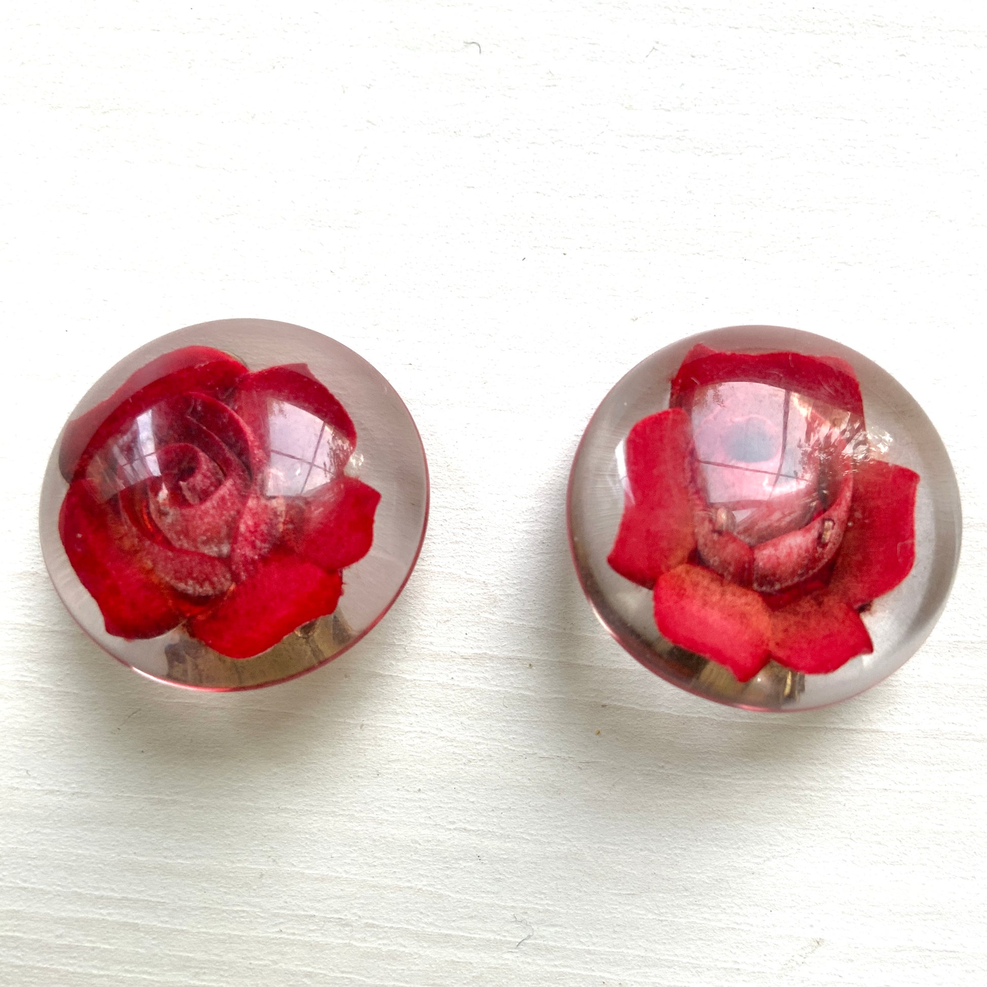 A beautiful pair of 1950s clip-on earrings featuring vivid red roses reverse carved into clear Lucite.  1950年代の赤いバラのインタリオのヴィンテージクリップイヤリング。