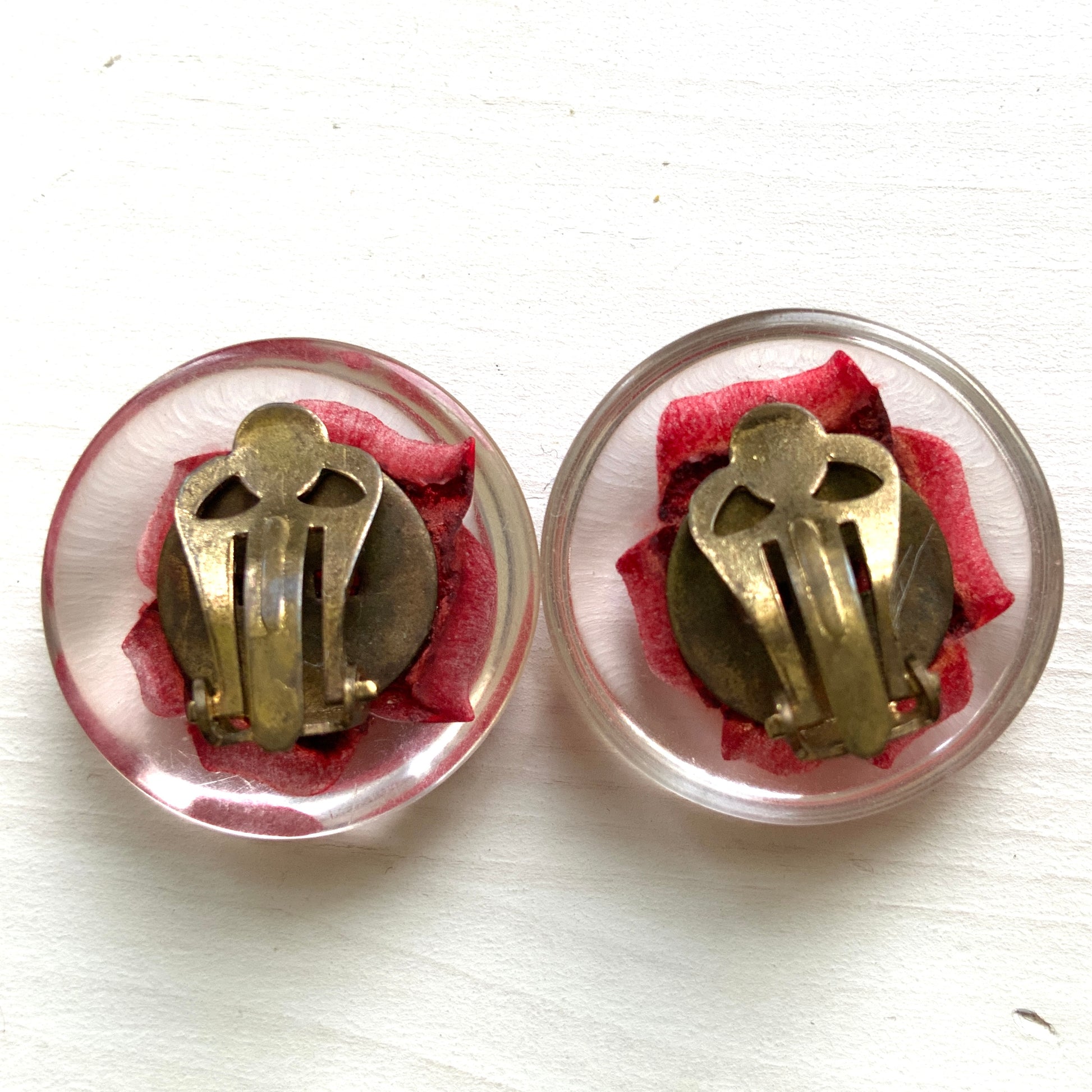 A beautiful pair of 1950s clip-on earrings featuring vivid red roses reverse carved into clear Lucite.  1950年代の赤いバラのインタリオのヴィンテージクリップイヤリング。
