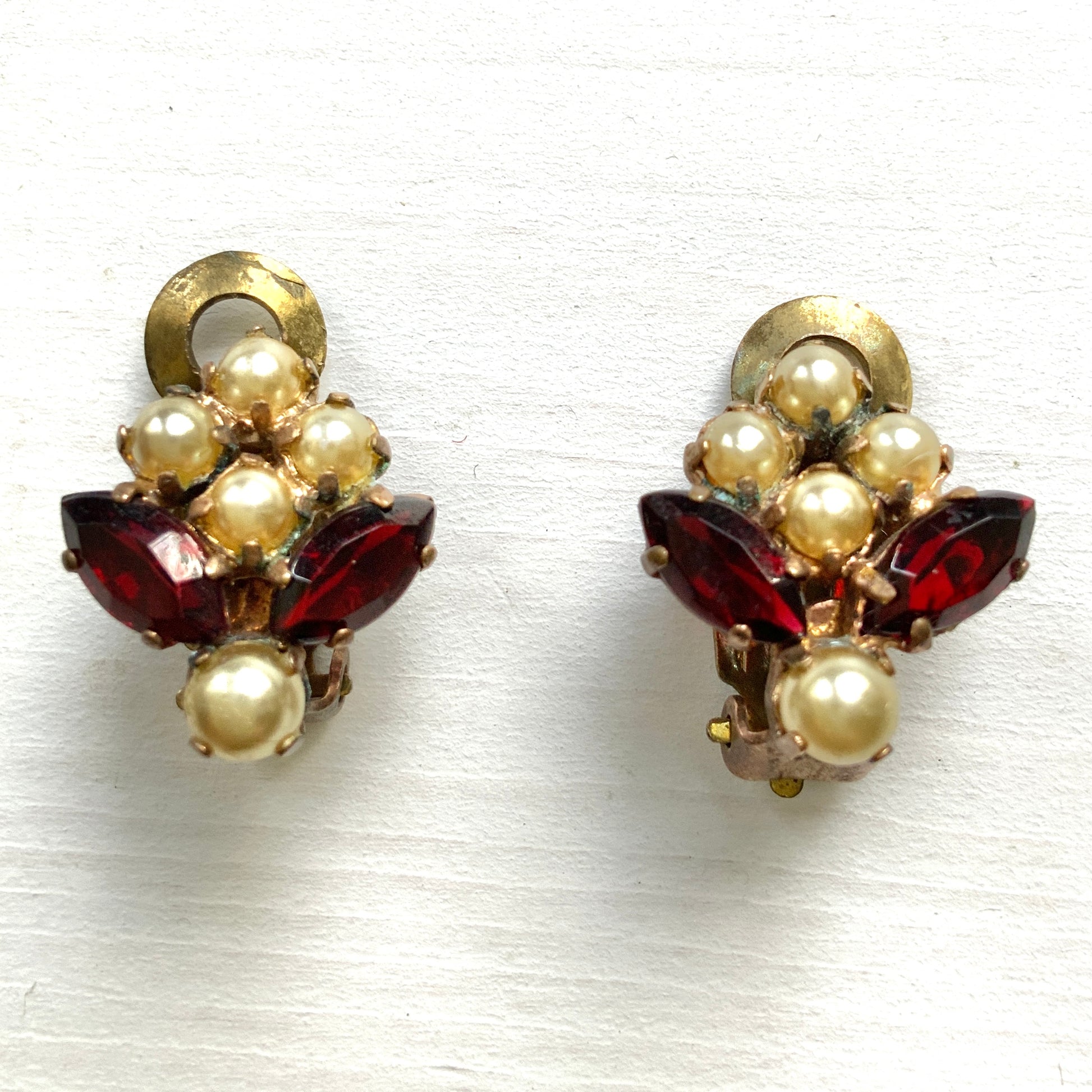 A charming pair of 1950s vintage clip-on earrings featuring deep ruby-red marquise-cut rhinestones and lustrous faux pearls in a classic floral design.  1950年代のフェイクパールとレッドラインストーンのヴィンテージクリップイヤリング。 