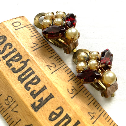 A charming pair of 1950s vintage clip-on earrings featuring deep ruby-red marquise-cut rhinestones and lustrous faux pearls in a classic floral design.  1950年代のフェイクパールとレッドラインストーンのヴィンテージクリップイヤリング。 
