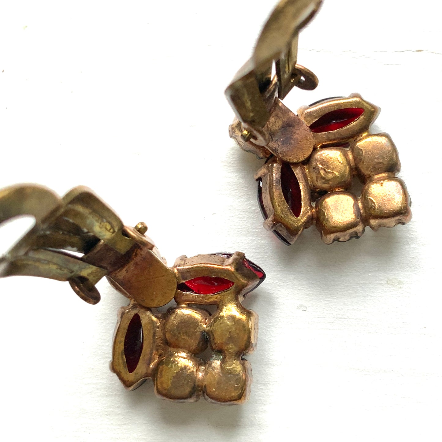 A charming pair of 1950s vintage clip-on earrings featuring deep ruby-red marquise-cut rhinestones and lustrous faux pearls in a classic floral design.  1950年代のフェイクパールとレッドラインストーンのヴィンテージクリップイヤリング。 