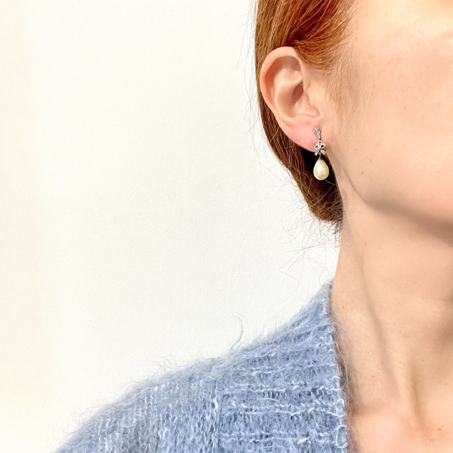 A pair of screw-back earrings featuring teardrop glass pearls suspended from silver bows. シルバー製のリボンに、ティアドロップのグラスパールが揺れるスクリューイヤリング。