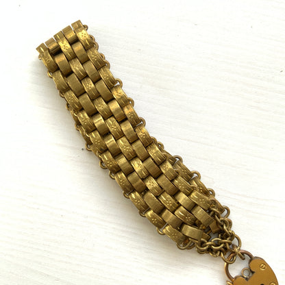 A bracelet featuring a heart-shaped padlock set on a heavy wide link chain. 重厚感のあるワイドリンクチェーンに、ハート型のパッドロックをあしらったブレスレット。