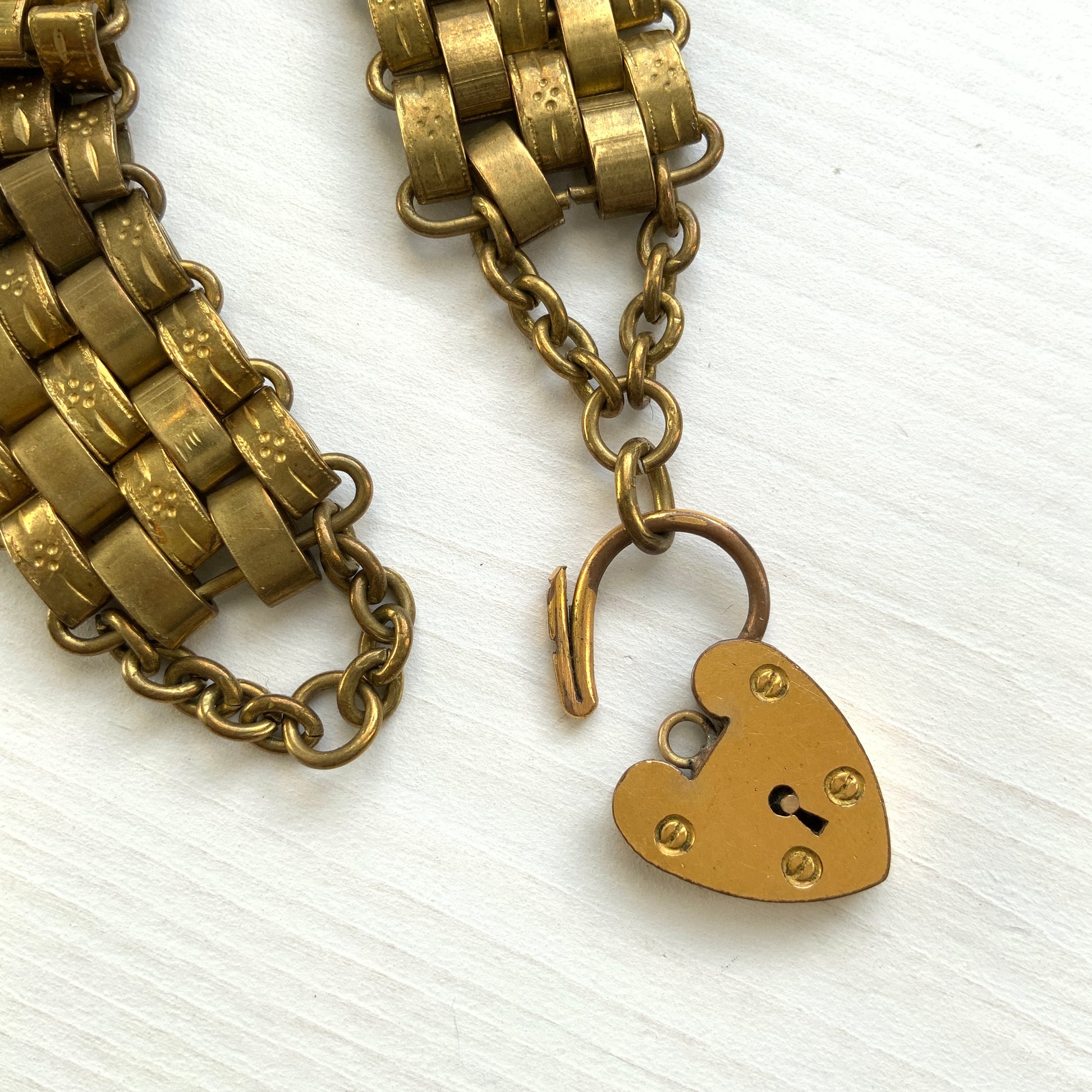 A bracelet featuring a heart-shaped padlock set on a heavy wide link chain. 重厚感のあるワイドリンクチェーンに、ハート型のパッドロックをあしらったブレスレット。