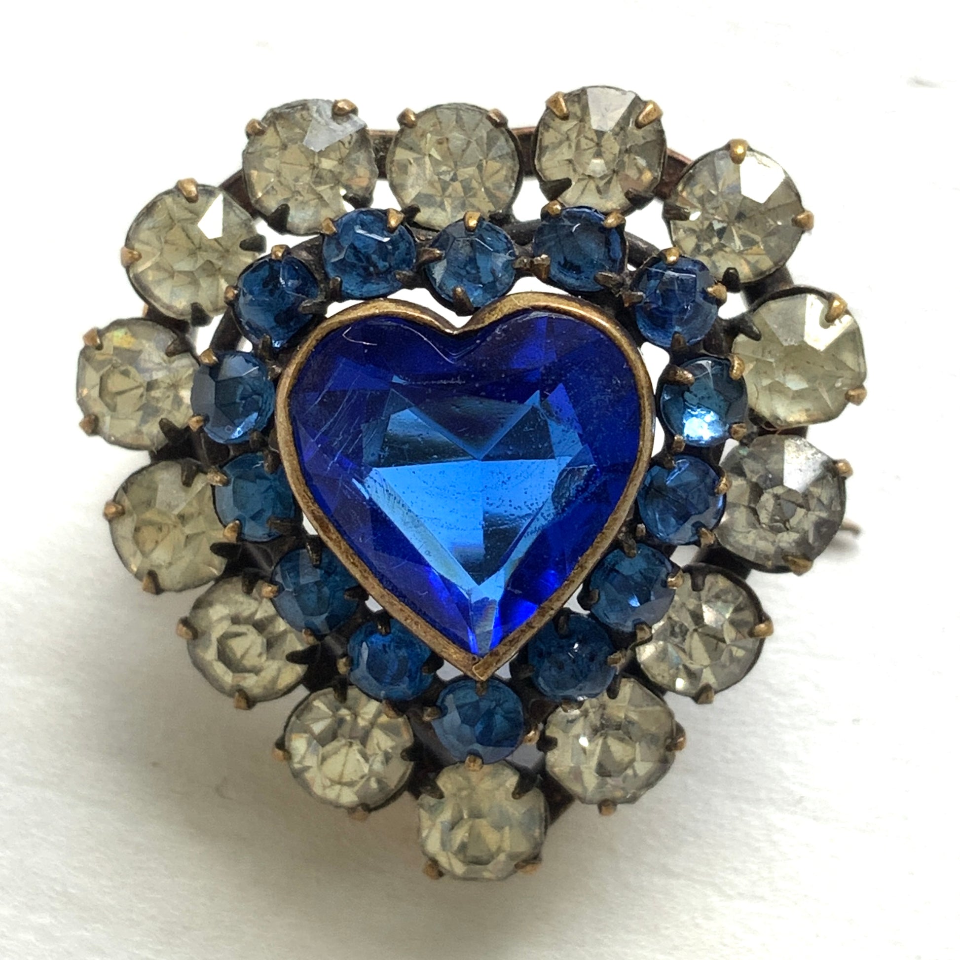 A charming heart-shaped mini brooch featuring a deep sea-blue glass centre. 深い海を思わせるブルーグラスが印象的な、ハートモチーフのミニブローチ。