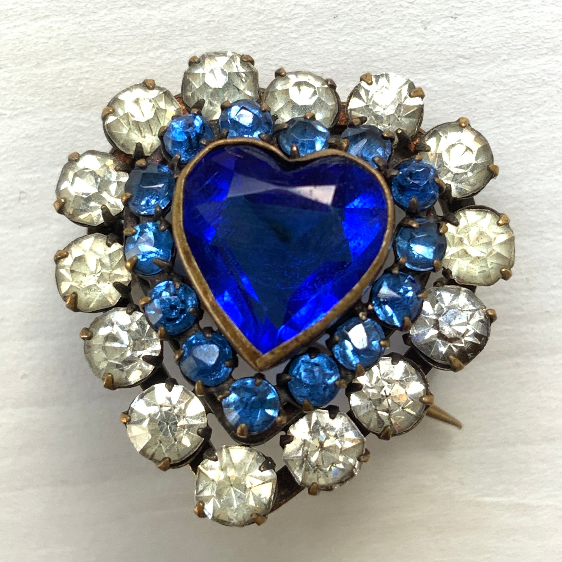 A charming heart-shaped mini brooch featuring a deep sea-blue glass centre. 深い海を思わせるブルーグラスが印象的な、ハートモチーフのミニブローチ。
