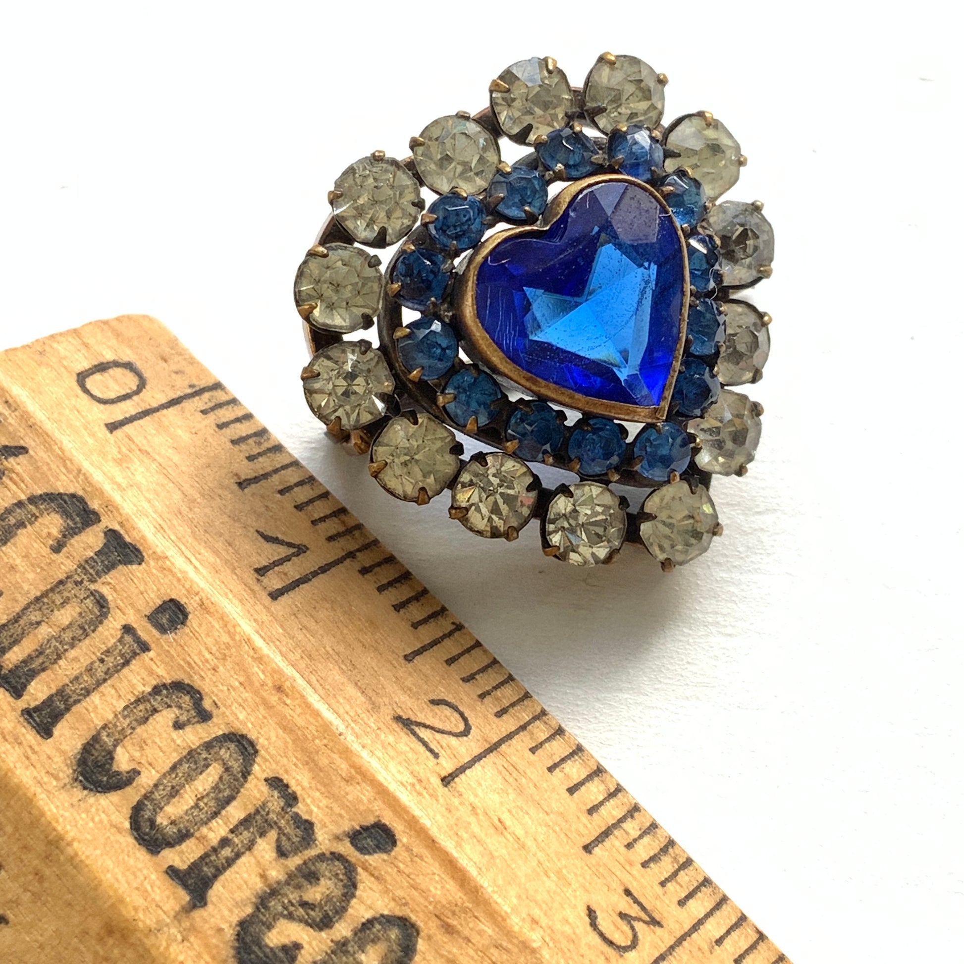A charming heart-shaped mini brooch featuring a deep sea-blue glass centre. 深い海を思わせるブルーグラスが印象的な、ハートモチーフのミニブローチ。