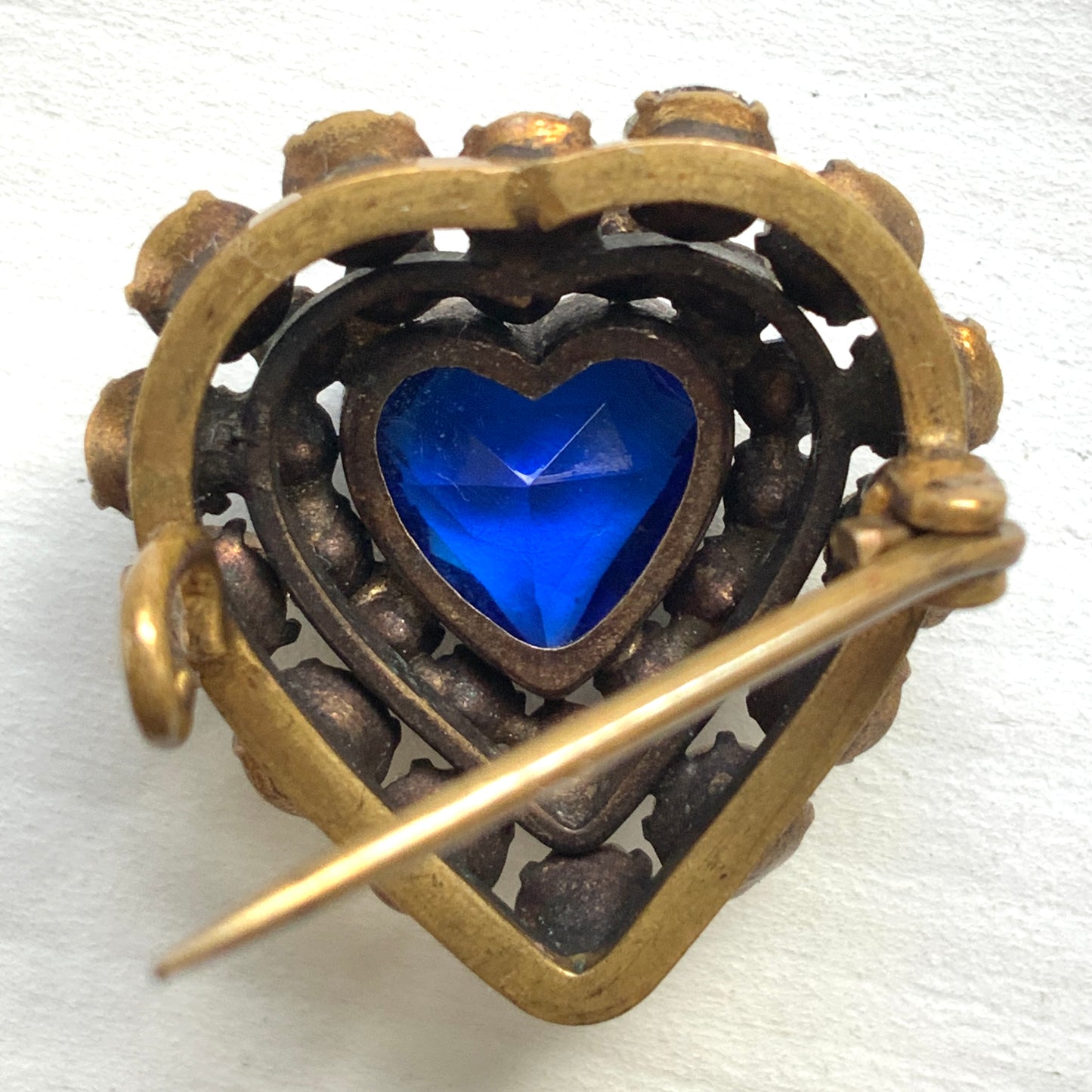 A charming heart-shaped mini brooch featuring a deep sea-blue glass centre. 深い海を思わせるブルーグラスが印象的な、ハートモチーフのミニブローチ。