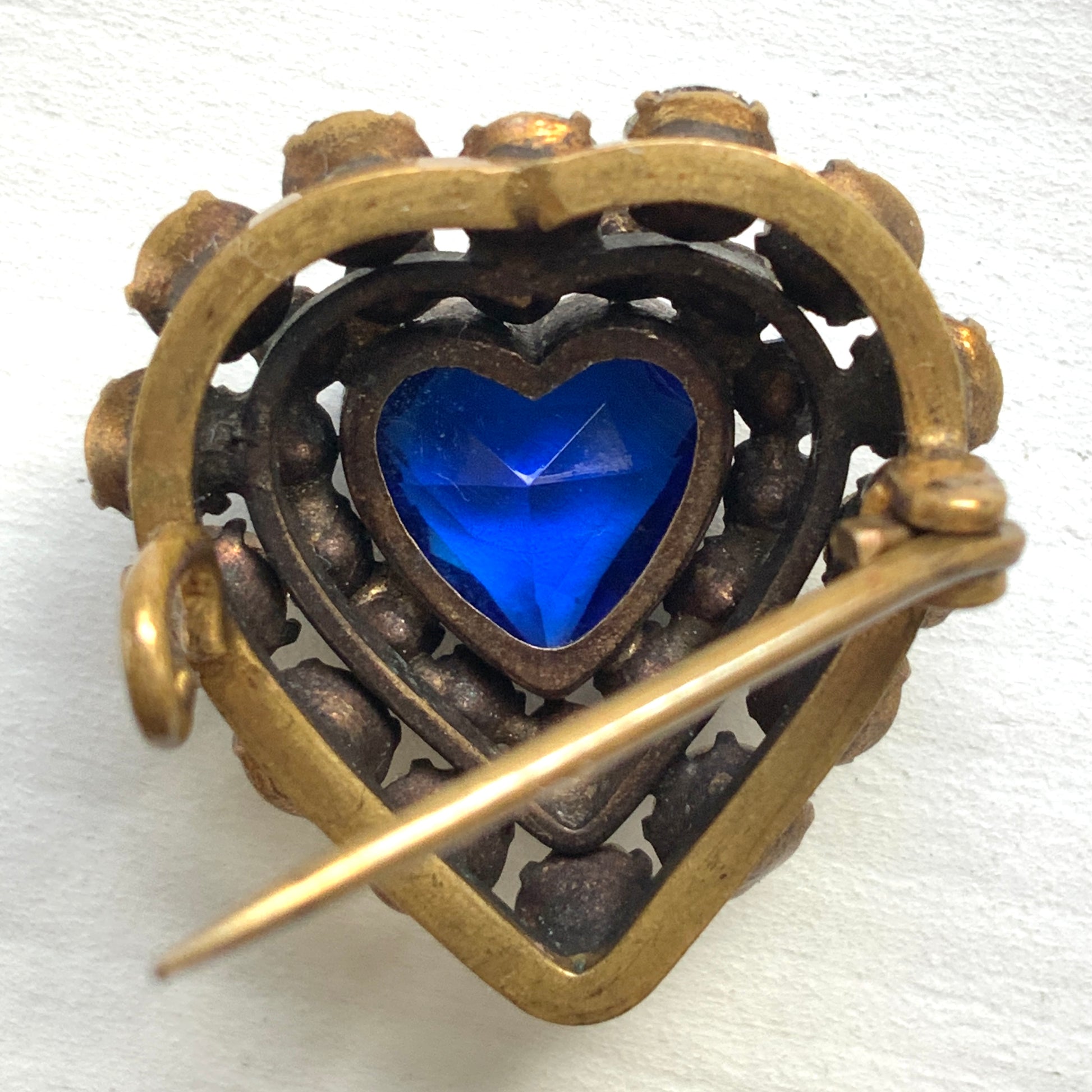 A charming heart-shaped mini brooch featuring a deep sea-blue glass centre. 深い海を思わせるブルーグラスが印象的な、ハートモチーフのミニブローチ。
