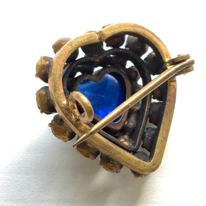 A charming heart-shaped mini brooch featuring a deep sea-blue glass centre. 深い海を思わせるブルーグラスが印象的な、ハートモチーフのミニブローチ。