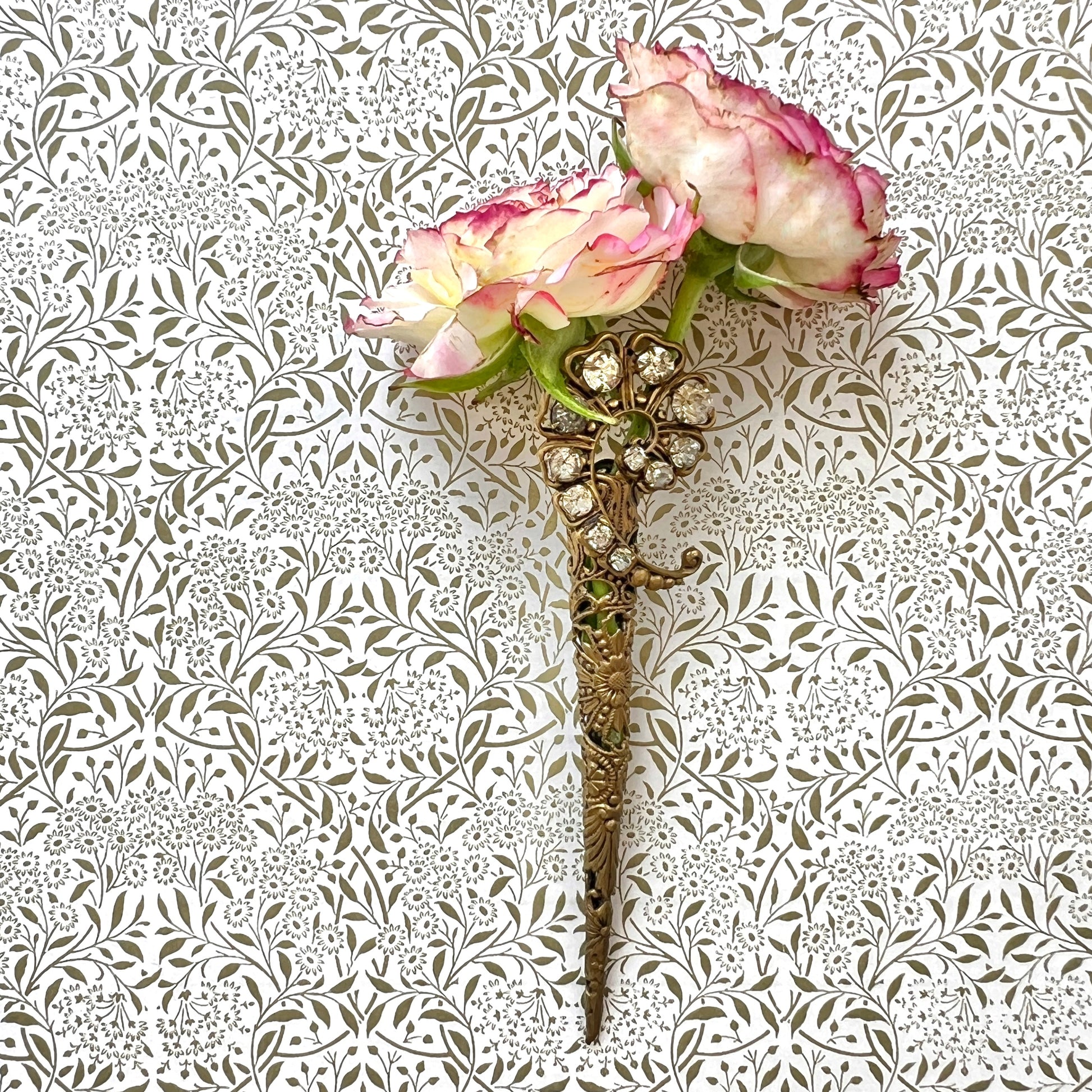 A decorative posy holder crafted from gold-tone filigree and adorned with sparkling rhinestones. ゴールドトーンのフィリグリーにラインストーンがあしらわれた、装飾的なポージーホルダー。
