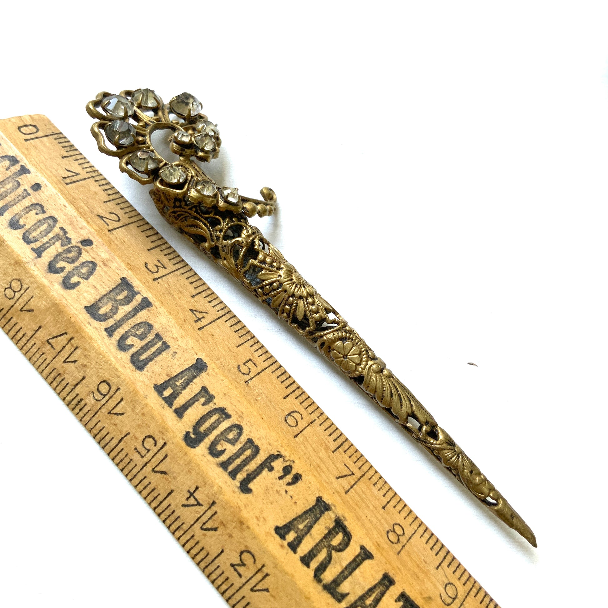 A decorative posy holder crafted from gold-tone filigree and adorned with sparkling rhinestones. ゴールドトーンのフィリグリーにラインストーンがあしらわれた、装飾的なポージーホルダー。
