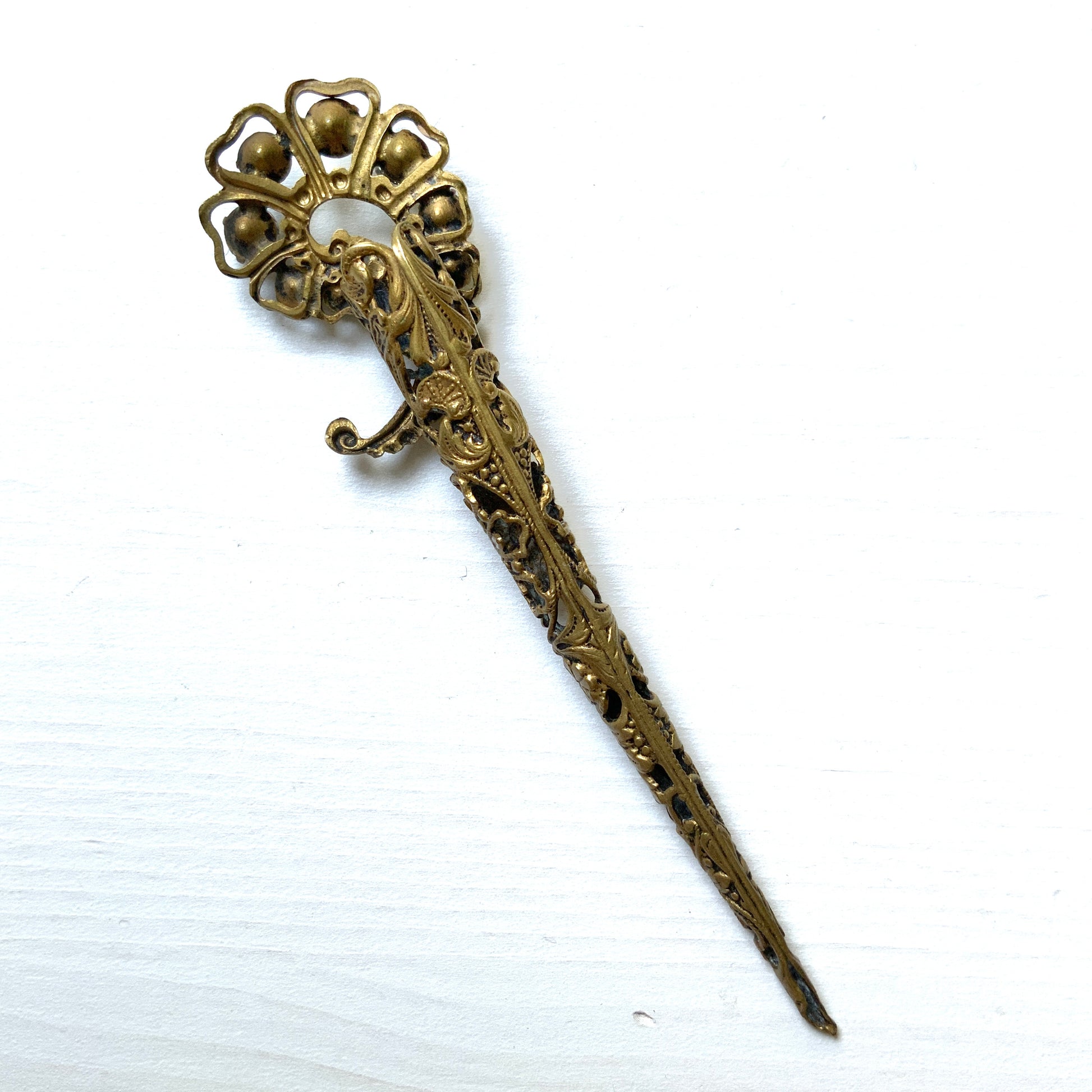A decorative posy holder crafted from gold-tone filigree and adorned with sparkling rhinestones. ゴールドトーンのフィリグリーにラインストーンがあしらわれた、装飾的なポージーホルダー。