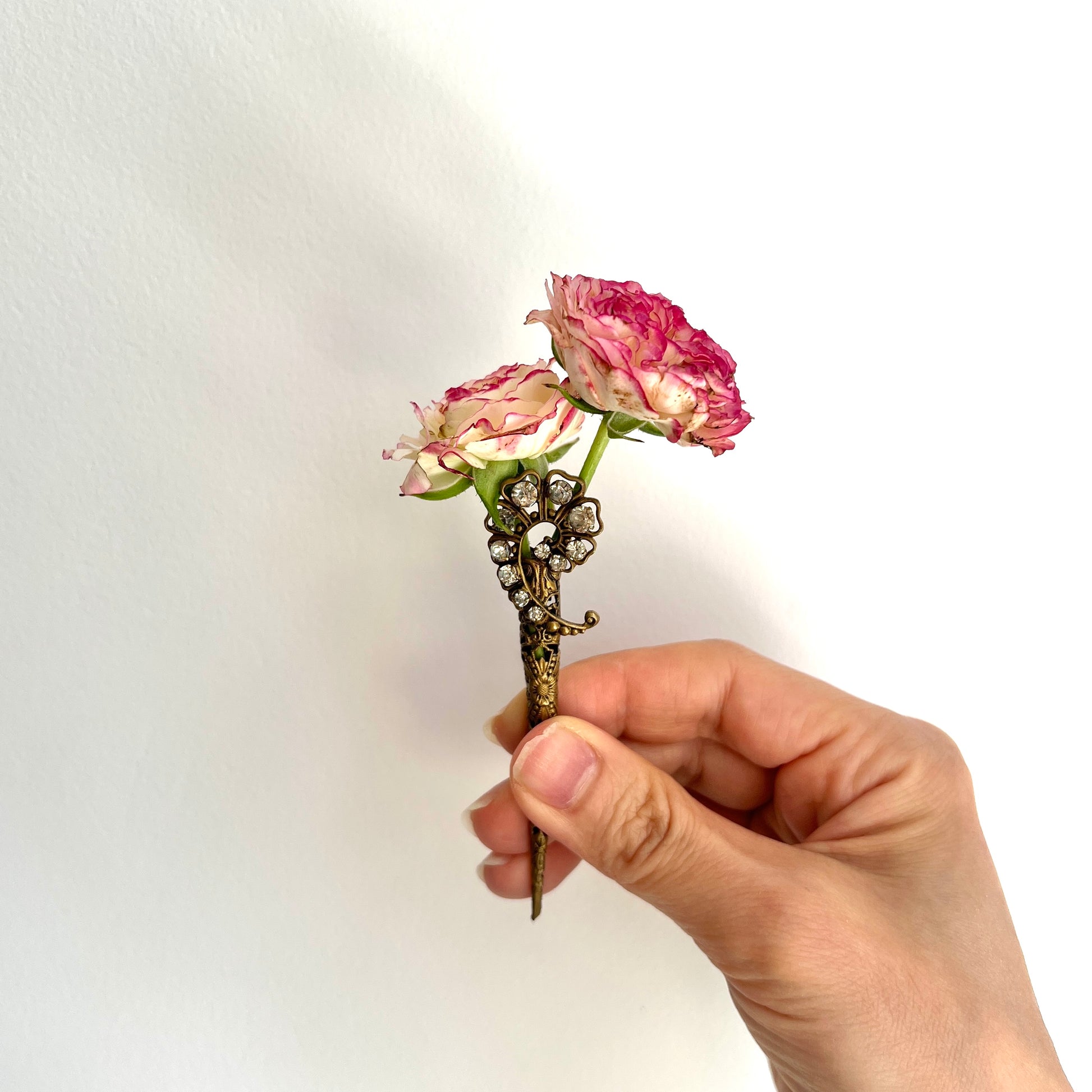 A decorative posy holder crafted from gold-tone filigree and adorned with sparkling rhinestones. ゴールドトーンのフィリグリーにラインストーンがあしらわれた、装飾的なポージーホルダー。