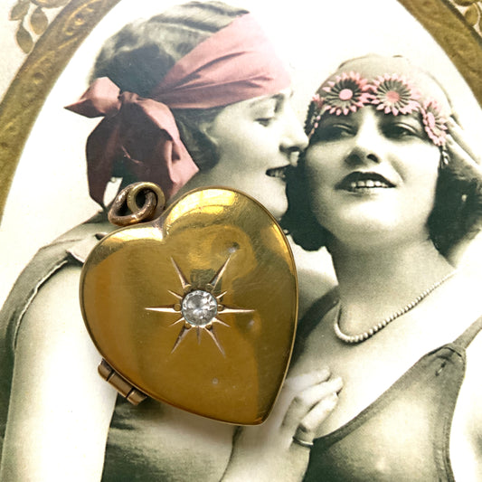 A gold-filled heart-shaped locket adorned with a small starburst motif. 小さなスターバーストモチーフがあしらわれた、ゴールドフィルドのハート型のロケット。