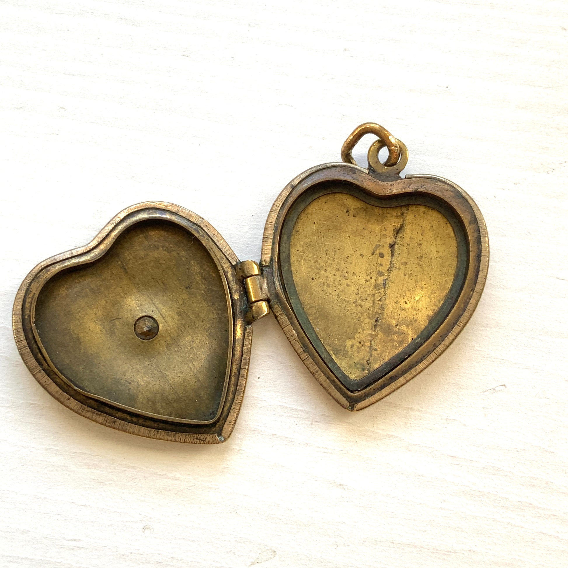 A gold-filled heart-shaped locket adorned with a small starburst motif. 小さなスターバーストモチーフがあしらわれた、ゴールドフィルドのハート型のロケット。