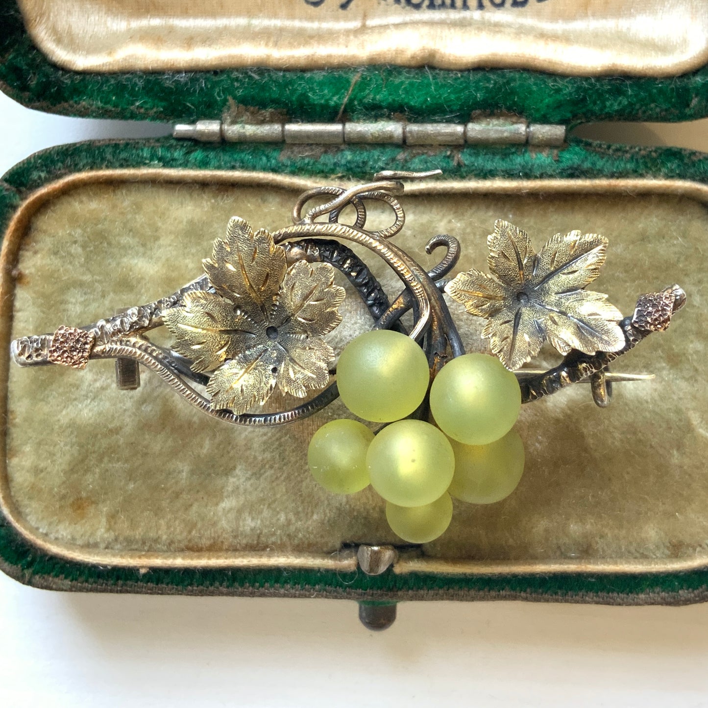 An antique silver brooch featuring a white grape motif set with frosted glass. アンティークのフロストグラスを使った白ブドウモチーフのシルバーブローチ。