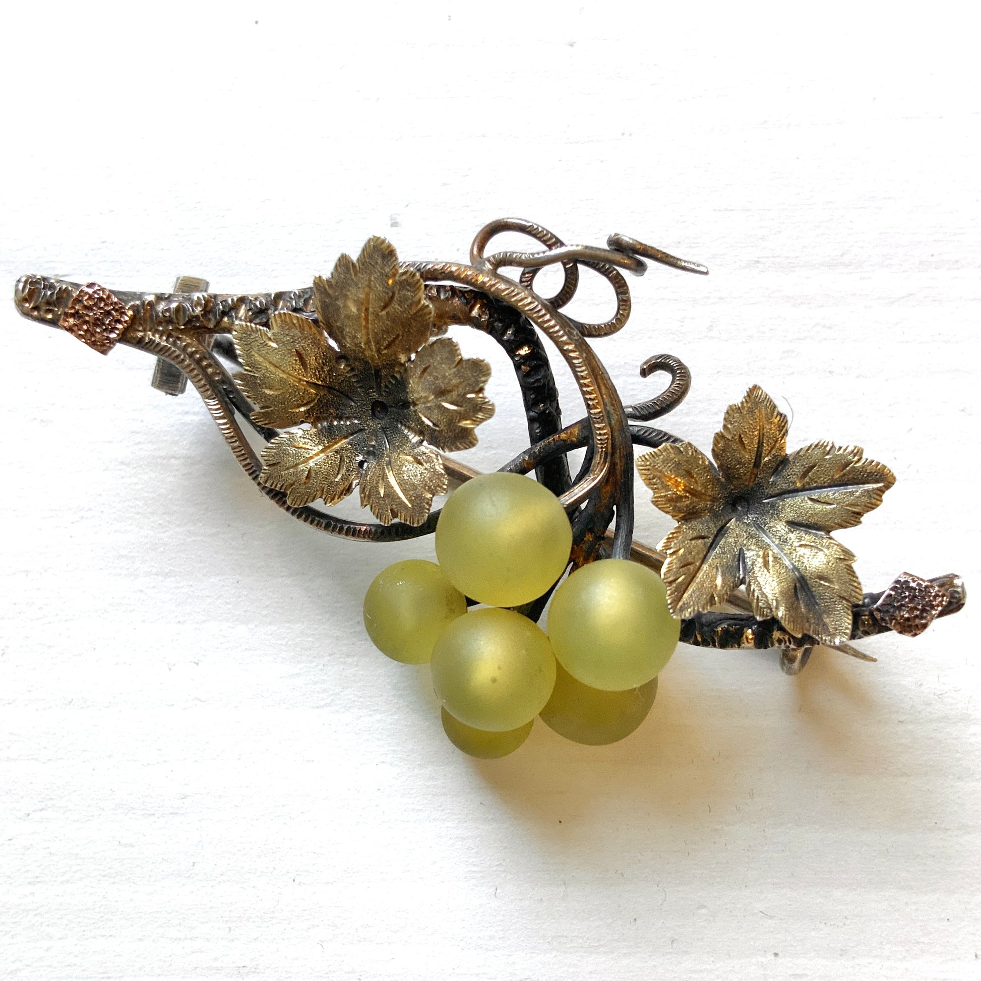 An antique silver brooch featuring a white grape motif set with frosted glass. アンティークのフロストグラスを使った白ブドウモチーフのシルバーブローチ。