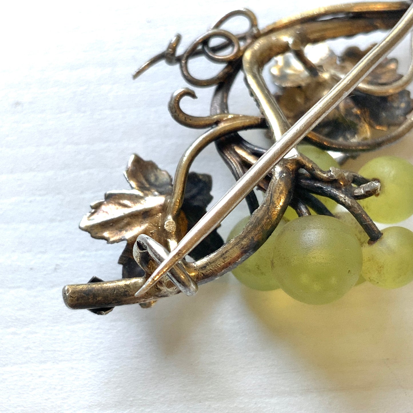 An antique silver brooch featuring a white grape motif set with frosted glass. アンティークのフロストグラスを使った白ブドウモチーフのシルバーブローチ。