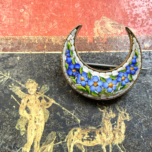 A crescent-shaped brooch adorned with charming blue micro-mosaic flowers resembling forget-me-nots. 勿忘草のような、かわいらしいブルーのお花のマイクロモザイク があしらわれた三日月型のブローチ。 