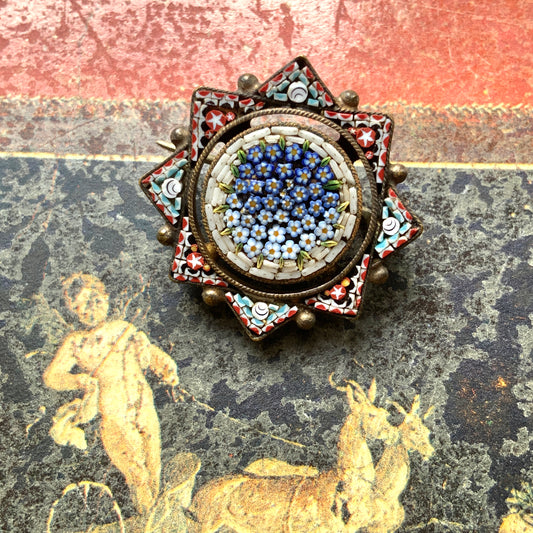 A star-shaped micro mosaic brooch filled with tiny, charming blue flowers reminiscent of forget-me-nots. 勿忘草のような、かわいらしい青い小花がぎっしりと詰め込まれた星型のマイクロモザイクブローチ。