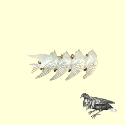 A brooch carved from mother of pearl, depicting a group of small birds. マザーオブパールに彫り出された小さな鳥たちのブローチ。