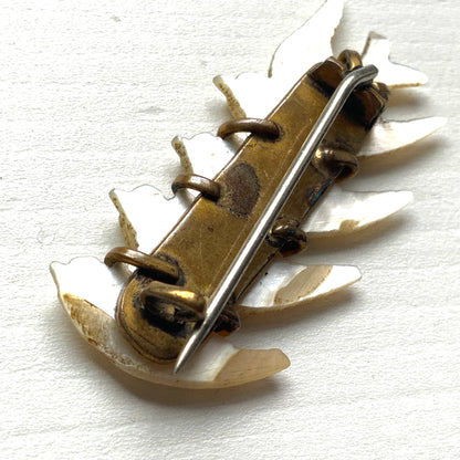 A brooch carved from mother of pearl, depicting a group of small birds. マザーオブパールに彫り出された小さな鳥たちのブローチ。
