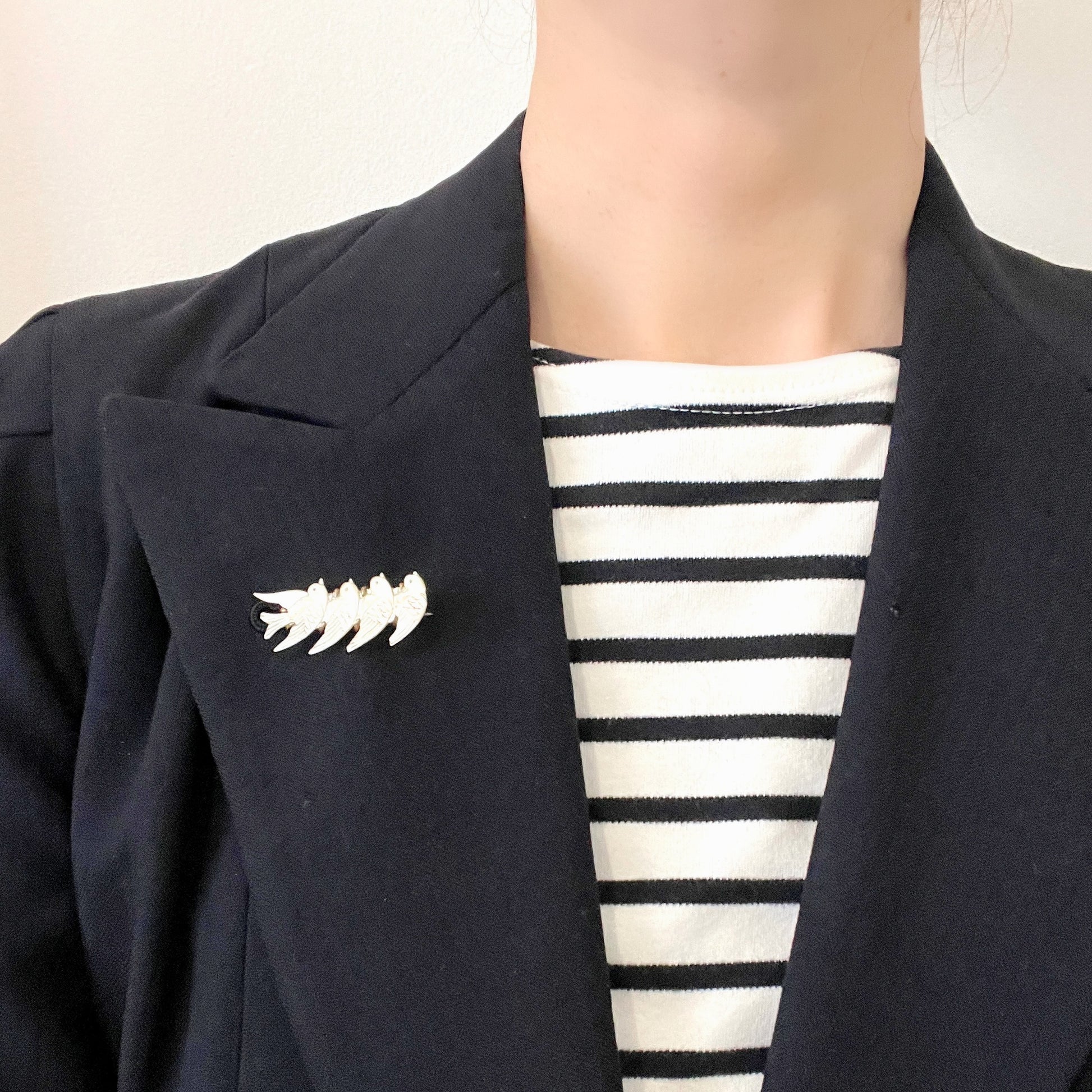 A brooch carved from mother of pearl, depicting a group of small birds. マザーオブパールに彫り出された小さな鳥たちのブローチ。