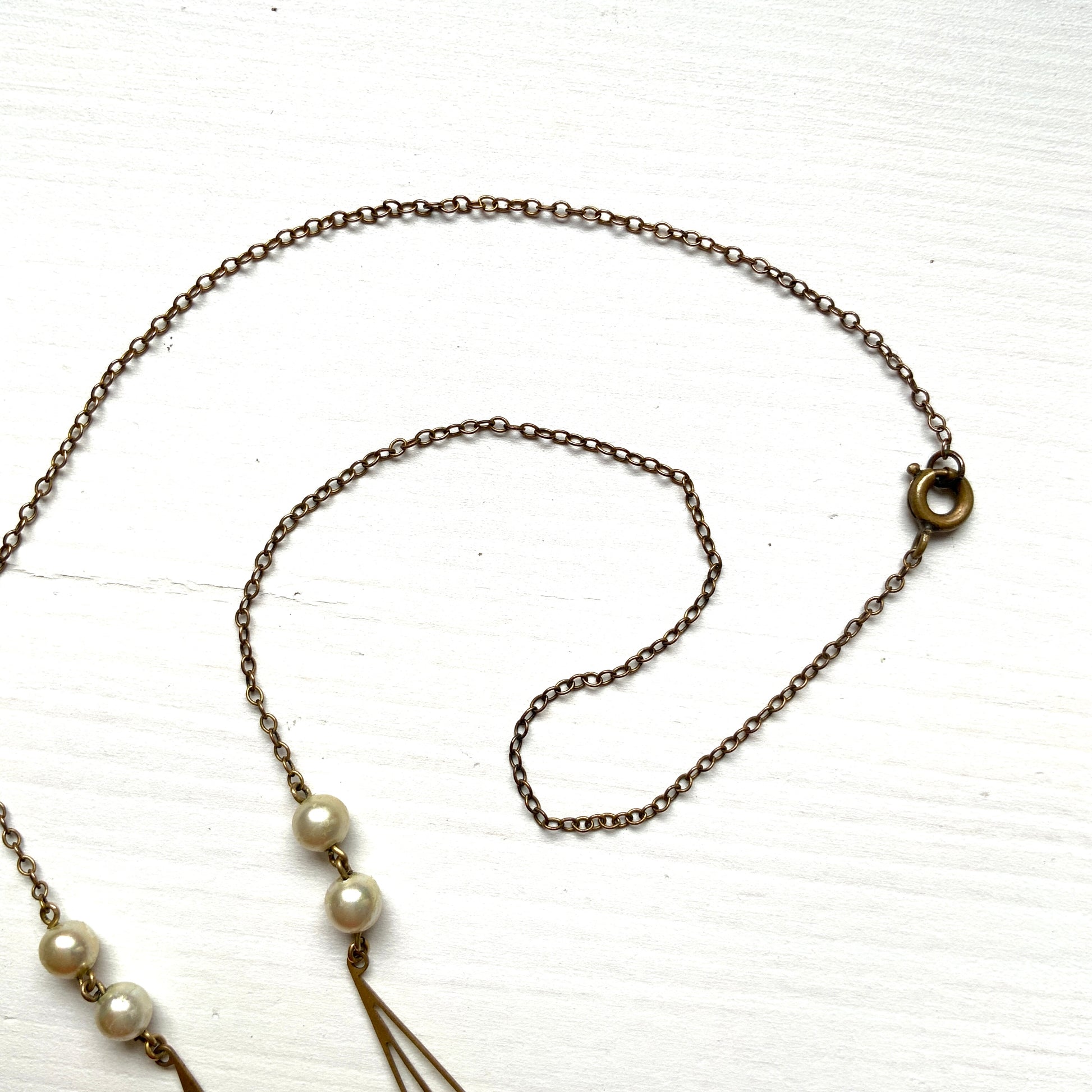 A necklace combining gold-tone metal links and glass pearls. ゴールドトーンメタルのリンクとグラスパールを組み合わせたネックレス。
