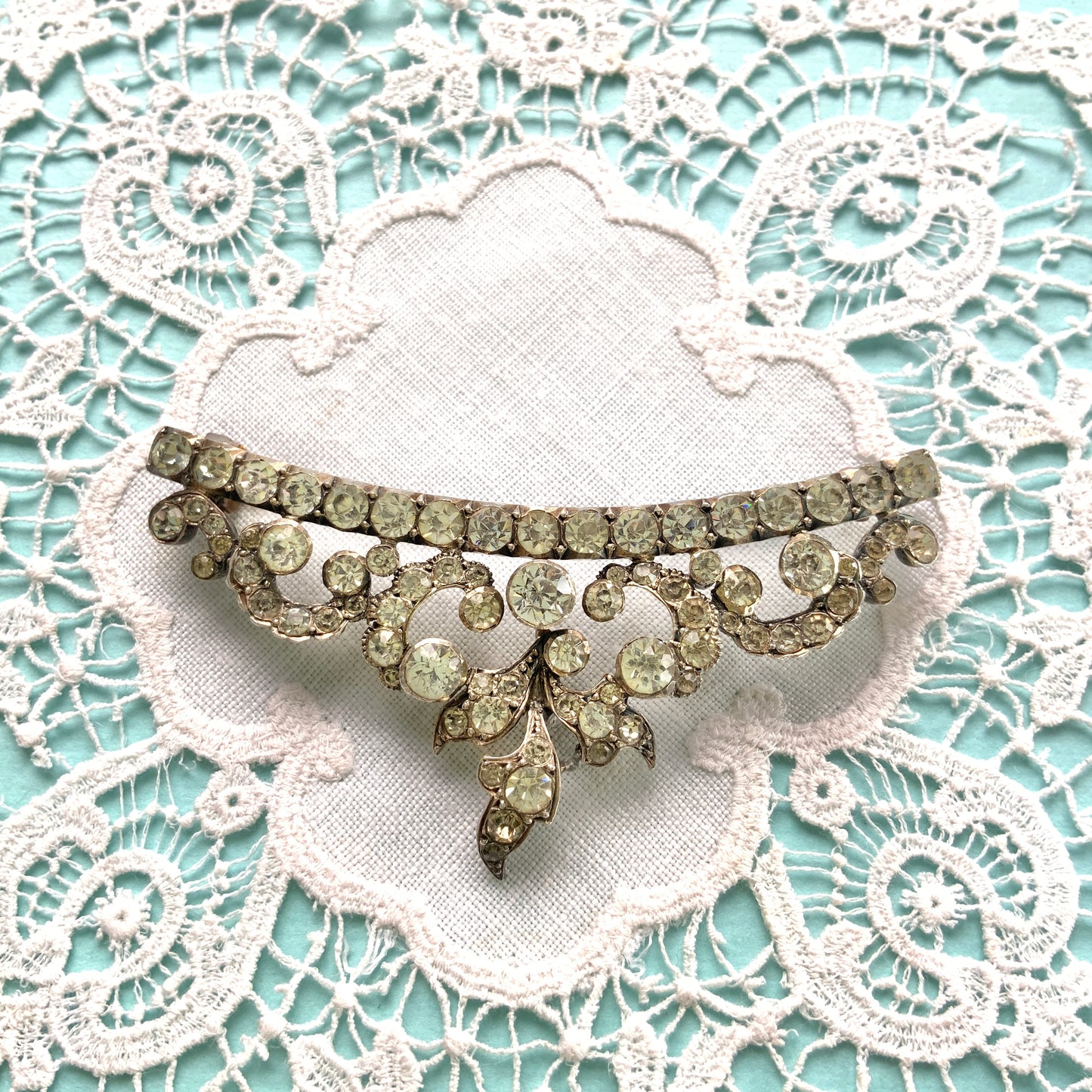A vintage rhinestone brooch with flowing leaf-like motifs and a gentle curved silhouette.  ラインストーンが連なり、葉っぱのようなモチーフがしなやかに広がるヴィンテージブローチ。 