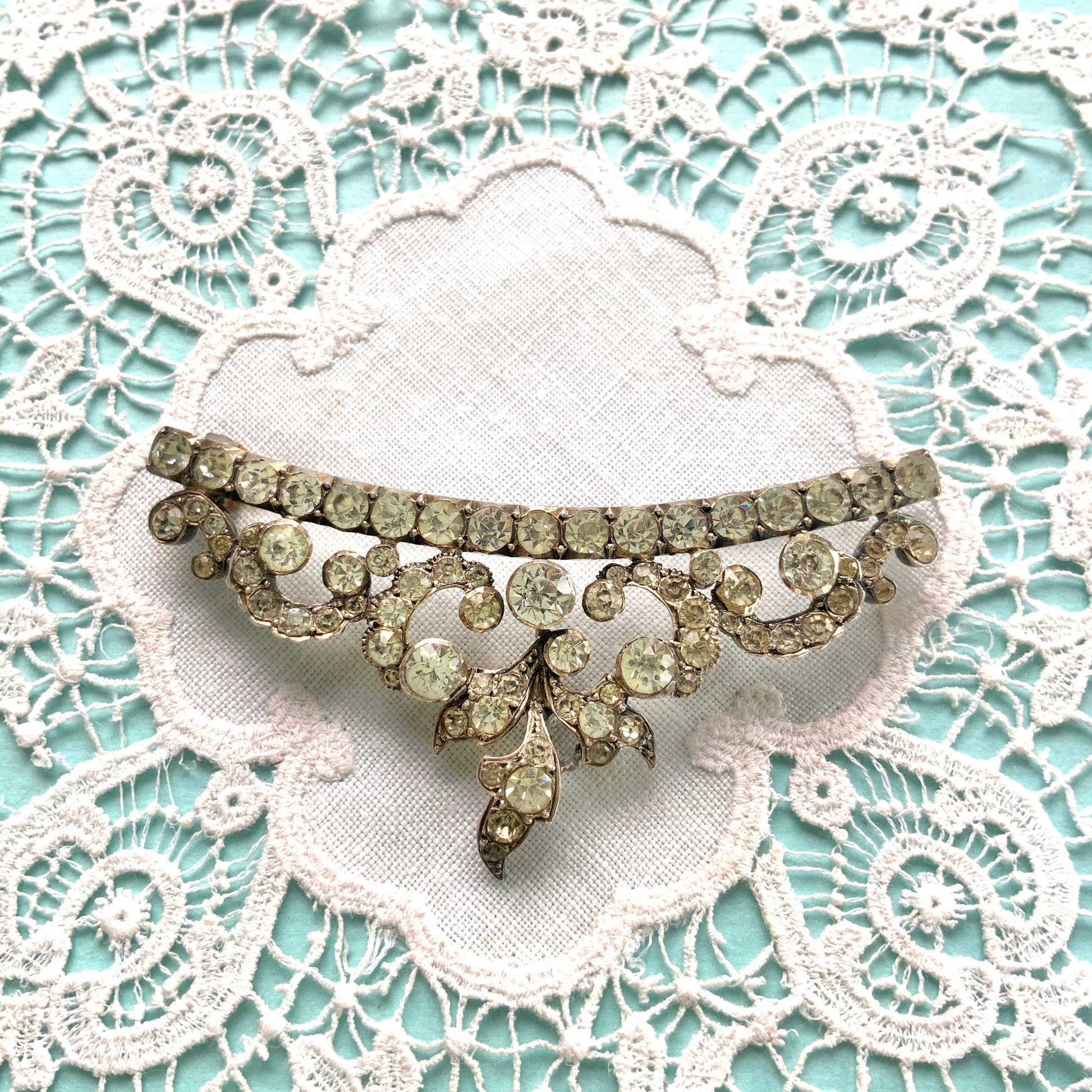 A vintage rhinestone brooch with flowing leaf-like motifs and a gentle curved silhouette.  ラインストーンが連なり、葉っぱのようなモチーフがしなやかに広がるヴィンテージブローチ。 