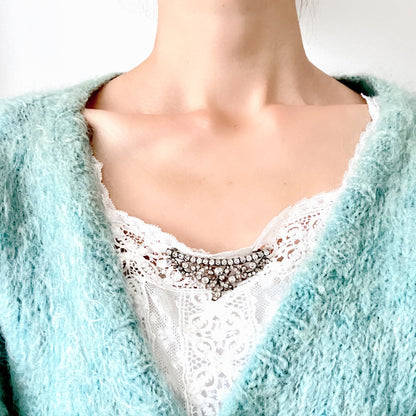 A vintage rhinestone brooch with flowing leaf-like motifs and a gentle curved silhouette.  ラインストーンが連なり、葉っぱのようなモチーフがしなやかに広がるヴィンテージブローチ。 