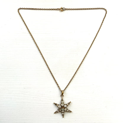 An antique pendant necklace featuring a starburst design with a mysterious glass stone known as Saphiret set in the centre. 神秘的な輝きを放つサフィレットを中央に添えた、ラインストーンのスターバーストデザインのペンダントネックレス。